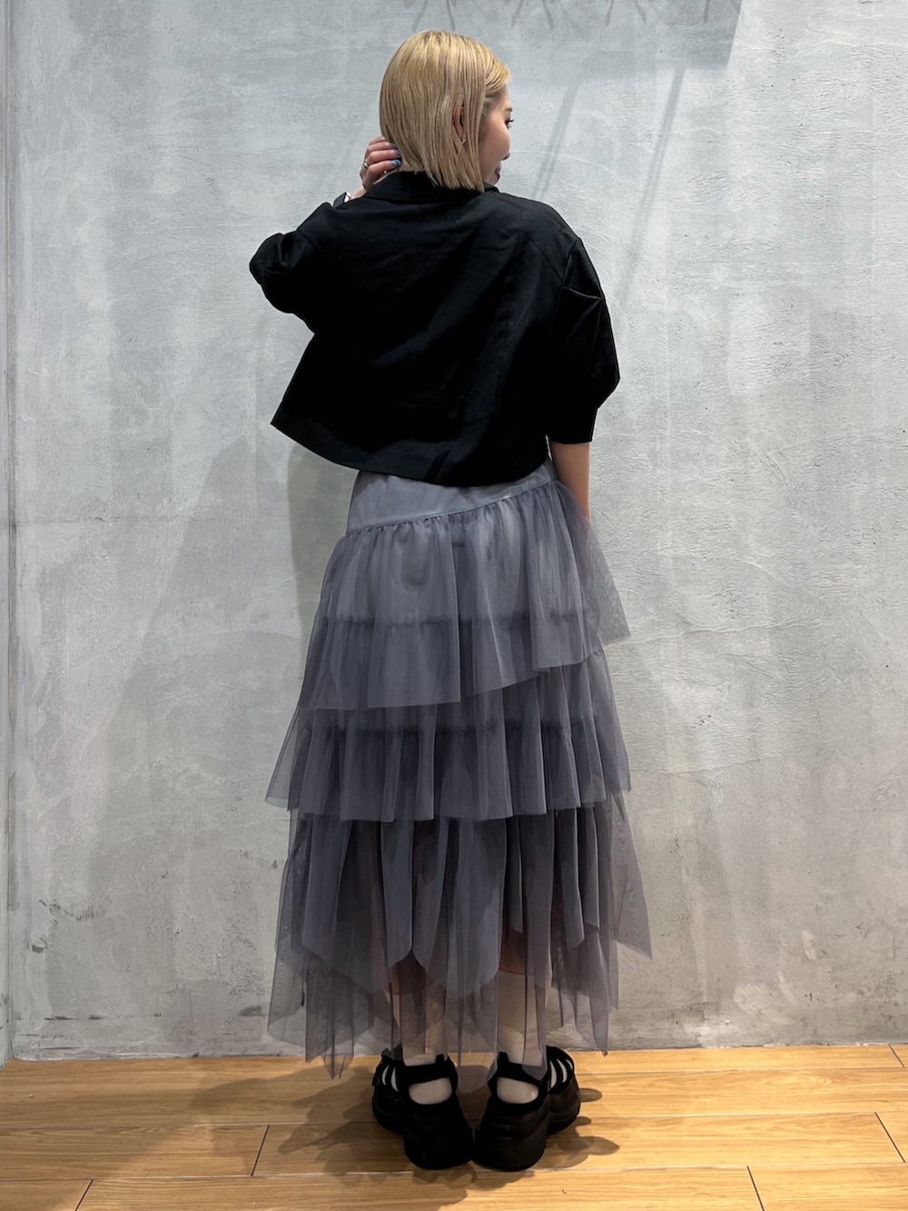 グレー系のスカート、ブラック系のテーラードジャケット、ブラック系のキャミソールを着用したレディースの夏コーディネートの4枚目の写真