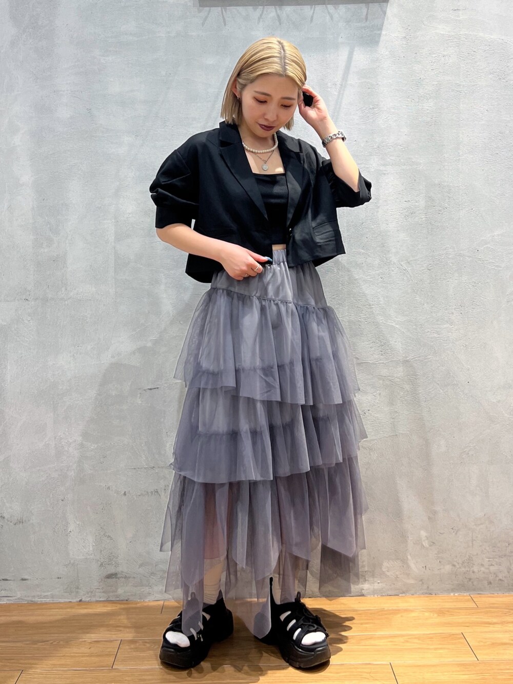 グレー系のスカート、ブラック系のテーラードジャケット、ブラック系のキャミソールを着用したレディースの夏コーディネートの2枚目の写真