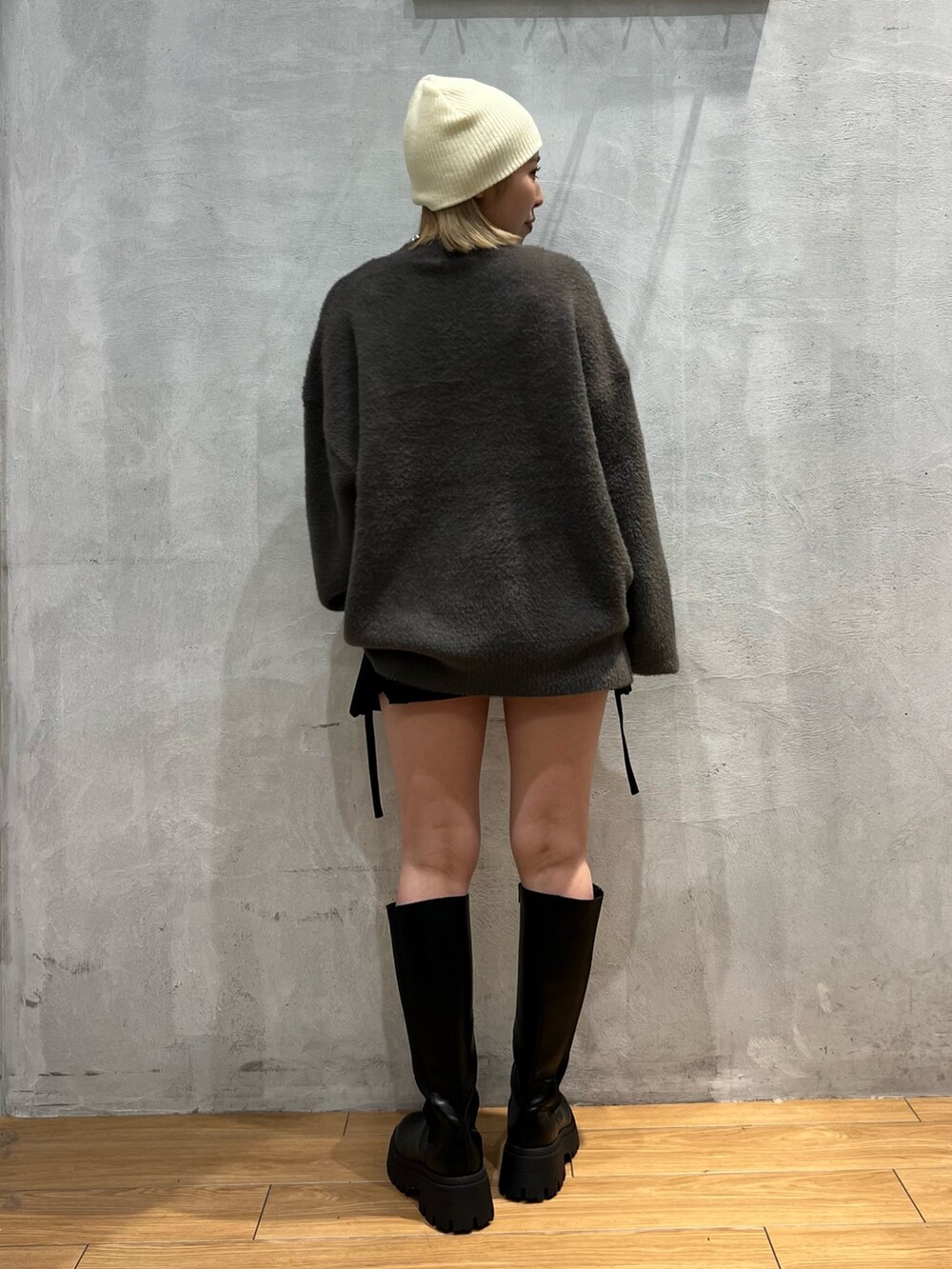 グレー系のニット/セーター、ブラック系のスカート、ブラック系のブーツを着用したレディースの秋コーディネートの3枚目の写真