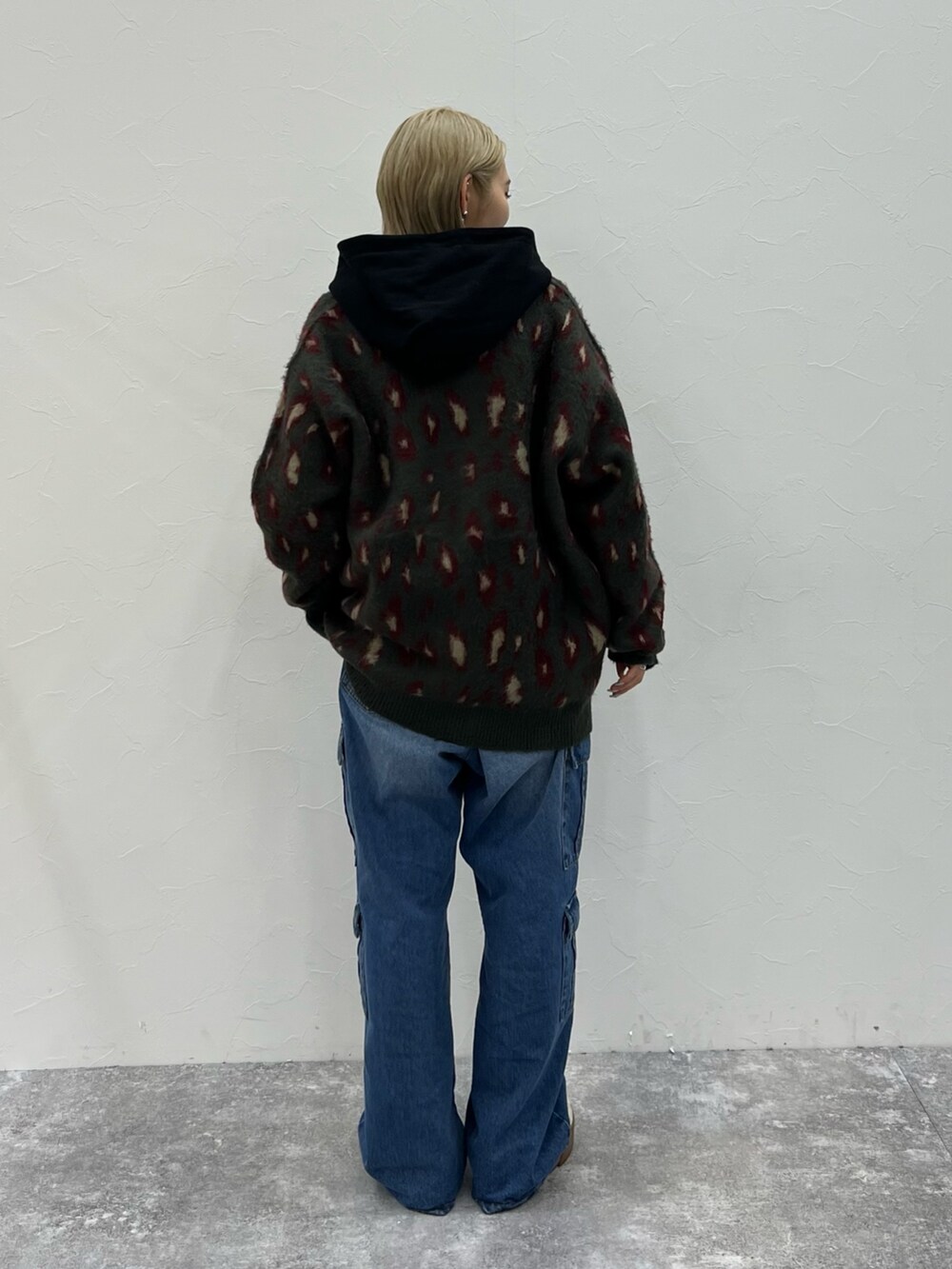 レッド系のカーディガン/ボレロ、ブラック系のパーカー、ブルー系のデニムパンツを着用したレディースの秋コーディネートの4枚目の写真