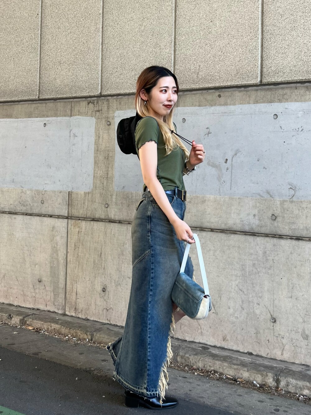 グリーン系のTシャツ/カットソー、ブルー系のデニムスカート、ブルー系のショルダーバッグを着用したレディースの春コーディネートの3枚目の写真