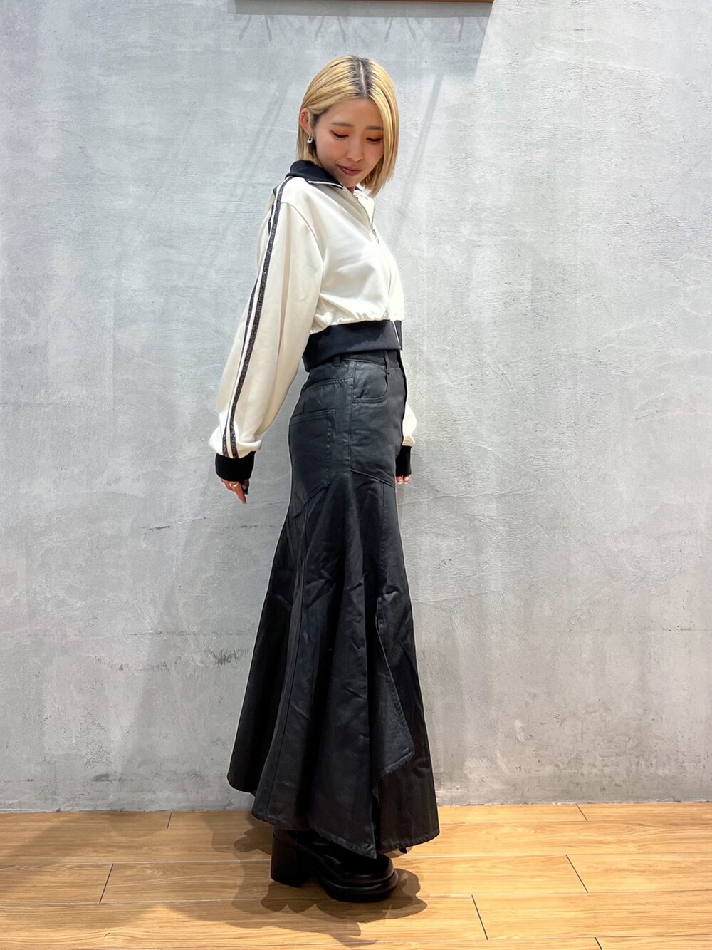 ホワイト系のジャケット/アウター、ブラック系のスカート、ブラック系のブーツを着用したレディースの秋コーディネートの2枚目の写真