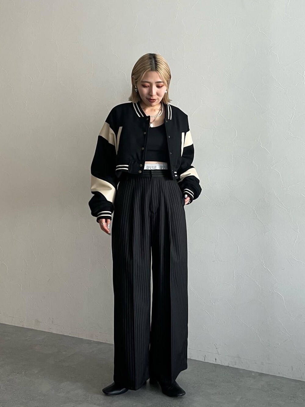 ブラック系のスラックス、ブラック系のスタジャンを着用したレディースの秋コーディネートの2枚目の写真