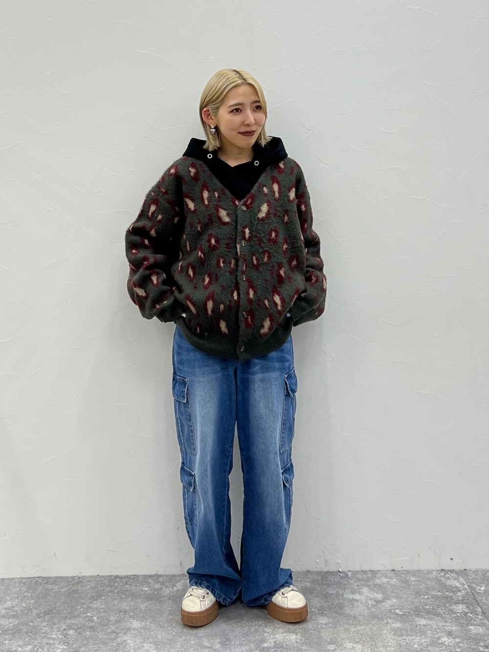 レッド系のカーディガン/ボレロ、ブラック系のパーカー、ブルー系のデニムパンツを着用したレディースの秋コーディネートの2枚目の写真