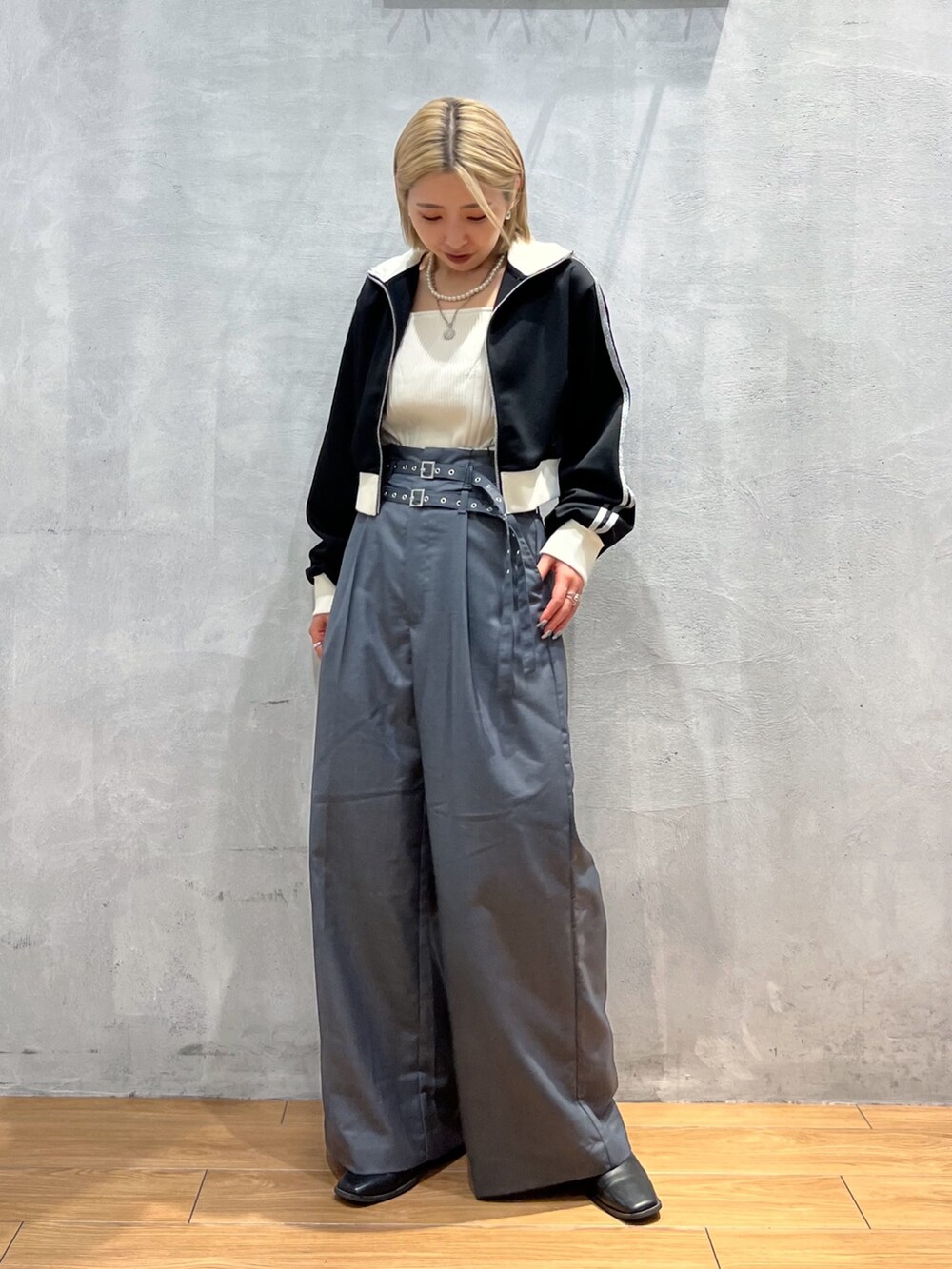 グレー系のスラックス、ブラック系のジャケット/アウター、ホワイト系のタンクトップを着用したレディースの秋コーディネートの2枚目の写真