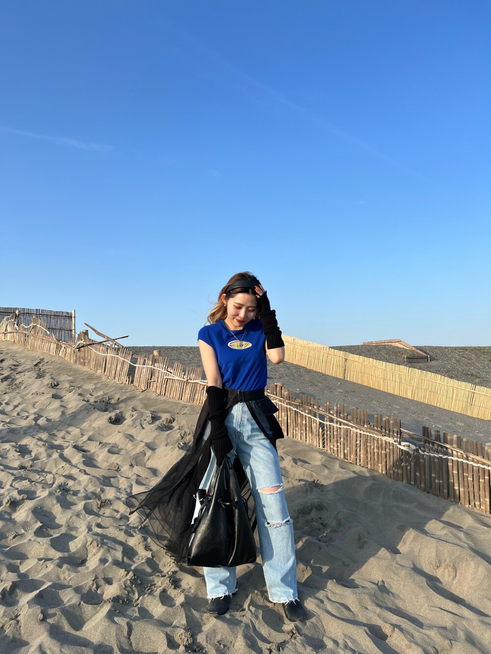 ブルー系のTシャツ/カットソー、ブラック系のスカート、ブルー系のデニムパンツを着用したレディースの春コーディネートの3枚目の写真