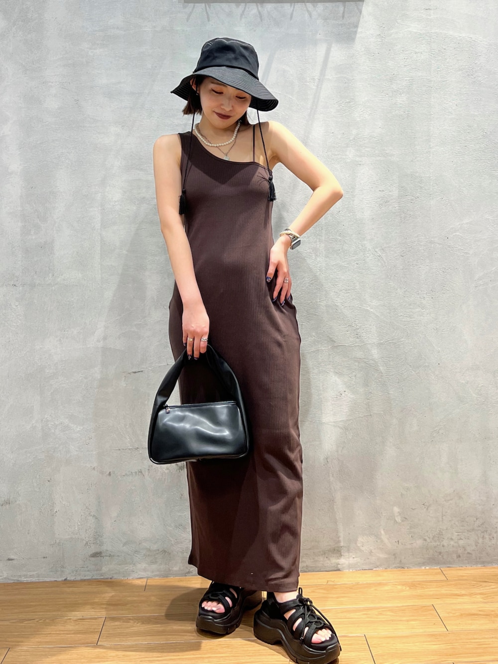 ブラウン系のワンピース、ブラック系のハンドバッグ、ブラック系のハットを着用したレディースの夏コーディネートの3枚目の写真
