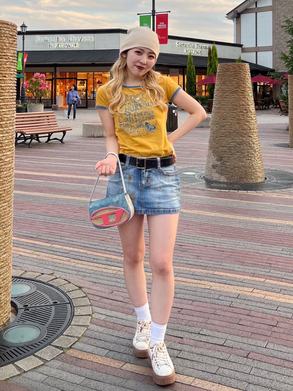 イエロー系のTシャツ/カットソー、ブルー系のデニムスカート、ブルー系のショルダーバッグを着用したレディースの春コーディネートの3枚目の写真