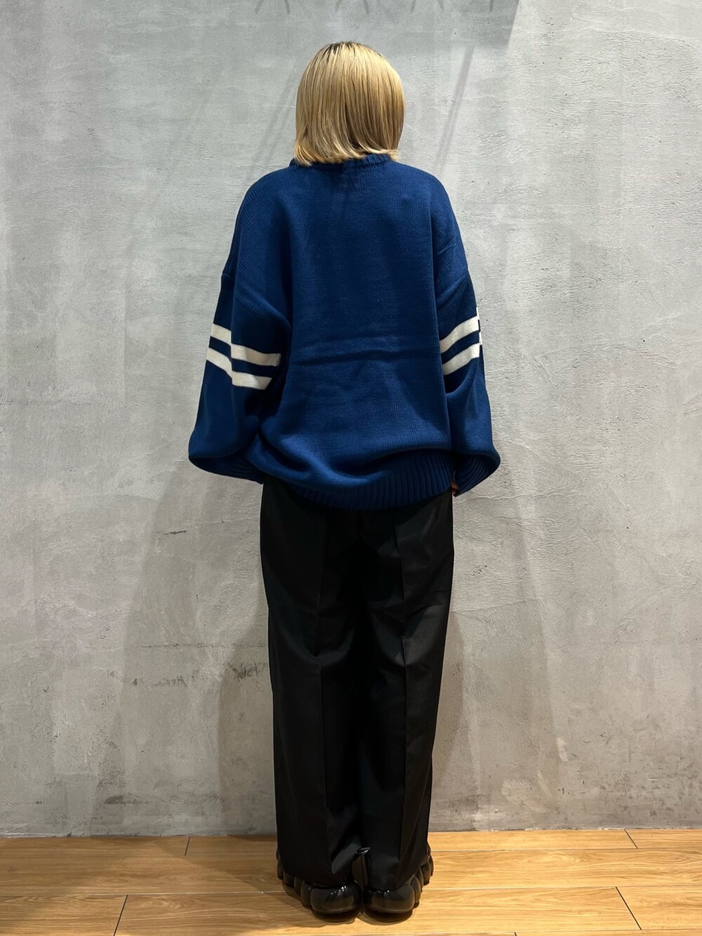 ブルー系のニット/セーター、ブラック系のスラックスを着用したレディースの秋コーディネートの3枚目の写真