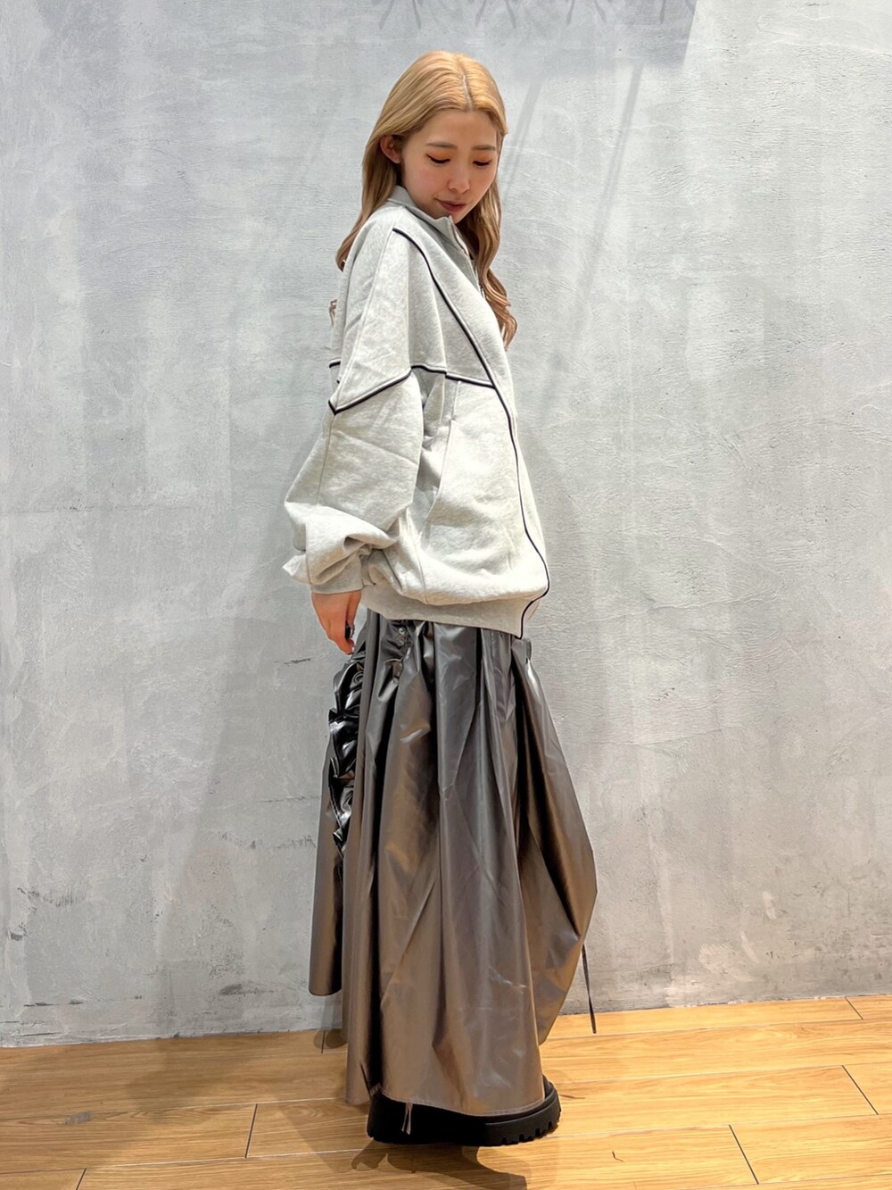 グレー系のスウェット、シルバー系のスカート、ブラック系のブーツを着用したレディースの秋コーディネートの2枚目の写真