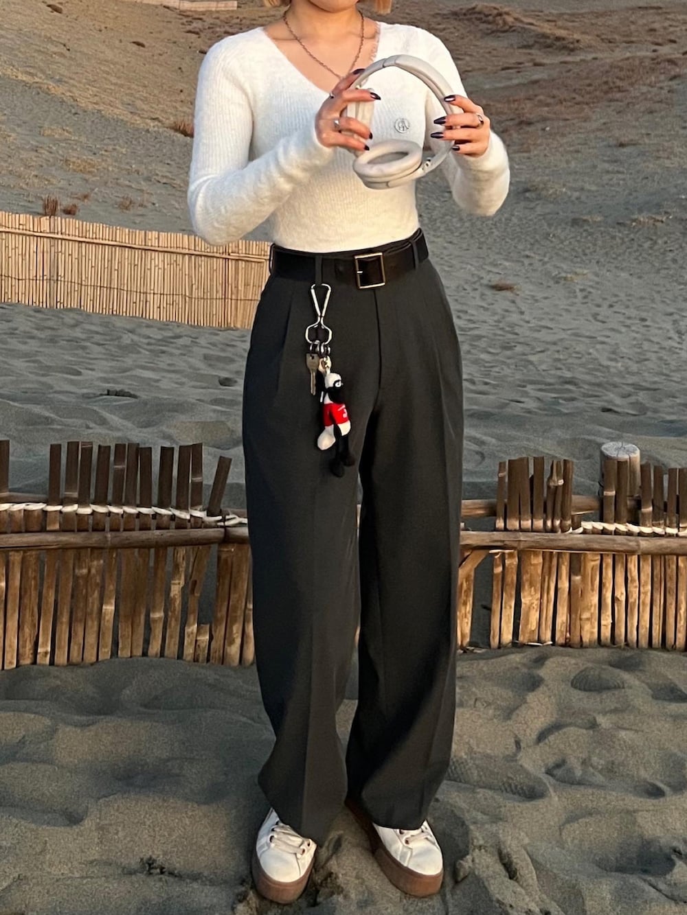 ホワイト系のニット/セーター、グレー系のスラックス、ベージュ系のスニーカーを着用したレディースの春コーディネートの4枚目の写真