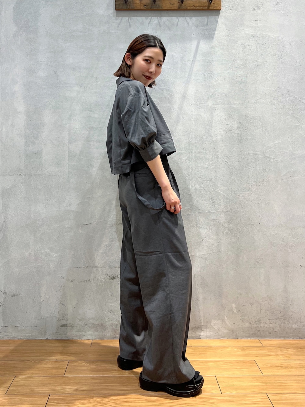 グレー系のスラックス、グレー系のテーラードジャケット、ホワイト系のキャミソールを着用したレディースの夏コーディネートの3枚目の写真