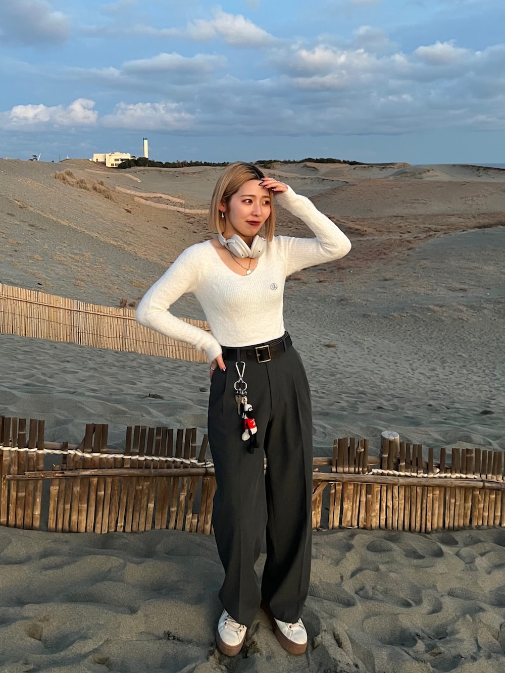 ホワイト系のニット/セーター、グレー系のスラックス、ベージュ系のスニーカーを着用したレディースの春コーディネートの3枚目の写真