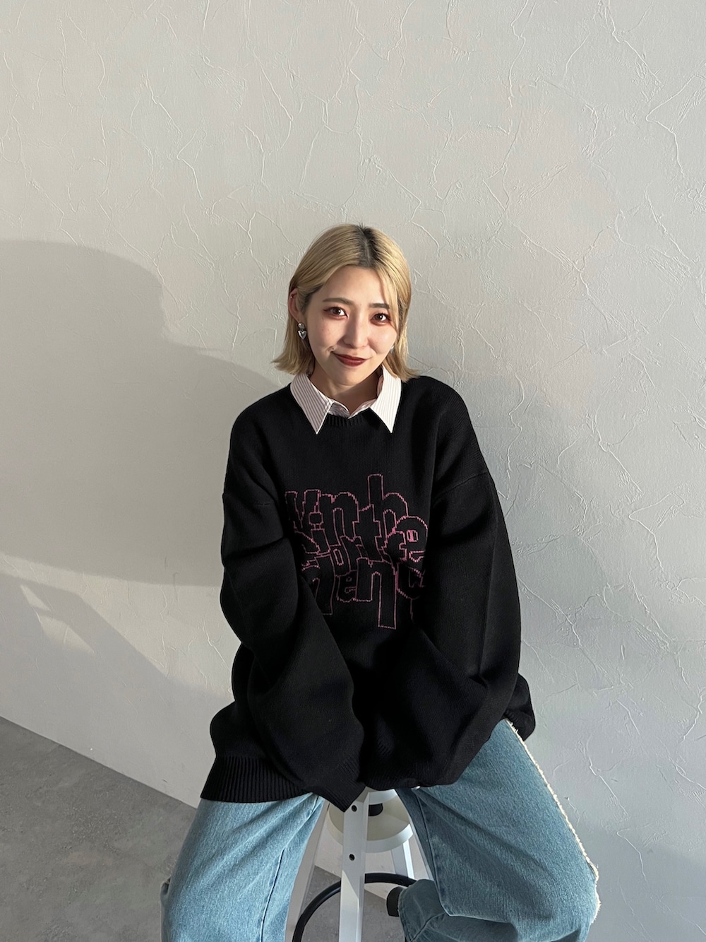ブラック系のニット/セーター、ブルー系のデニムパンツ、ピンク系のシャツ/ブラウスを着用したレディースの秋コーディネートの3枚目の写真