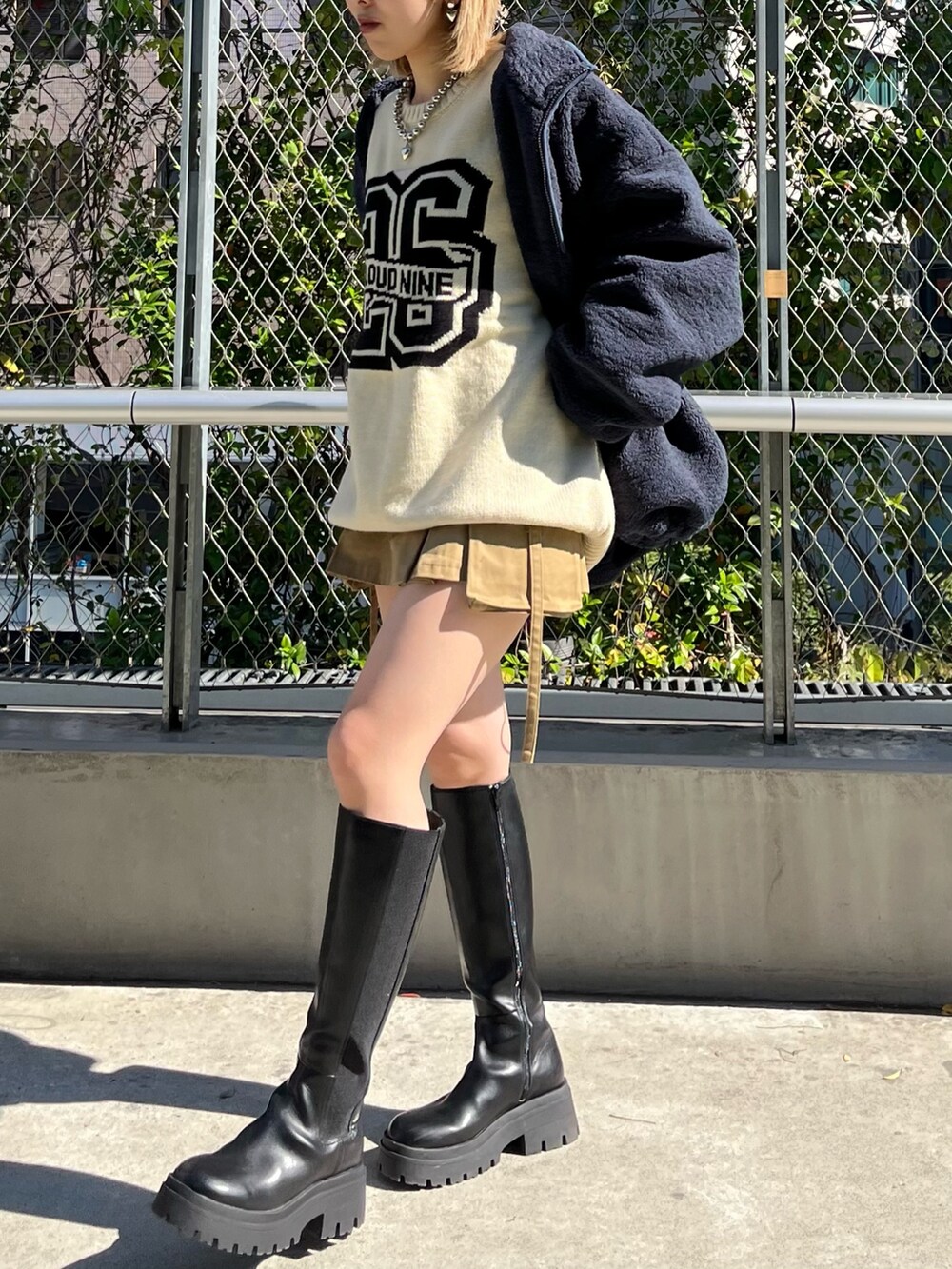 ブルー系のブルゾン、ホワイト系のニット/セーター、ベージュ系のスカートを着用したレディースの秋コーディネートの4枚目の写真