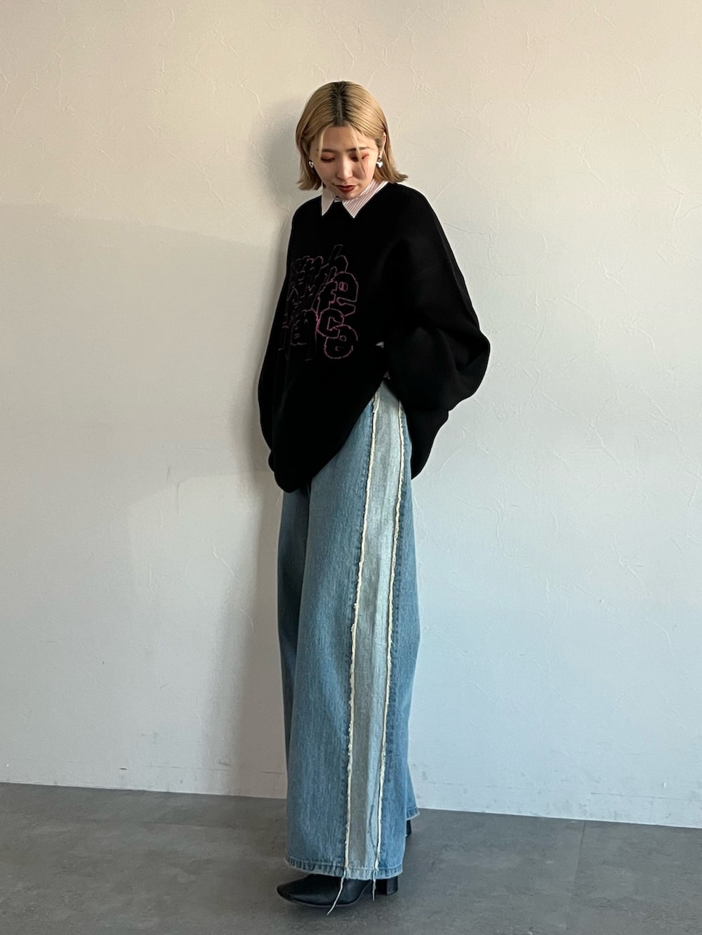ブラック系のニット/セーター、ブルー系のデニムパンツ、ピンク系のシャツ/ブラウスを着用したレディースの秋コーディネートの4枚目の写真