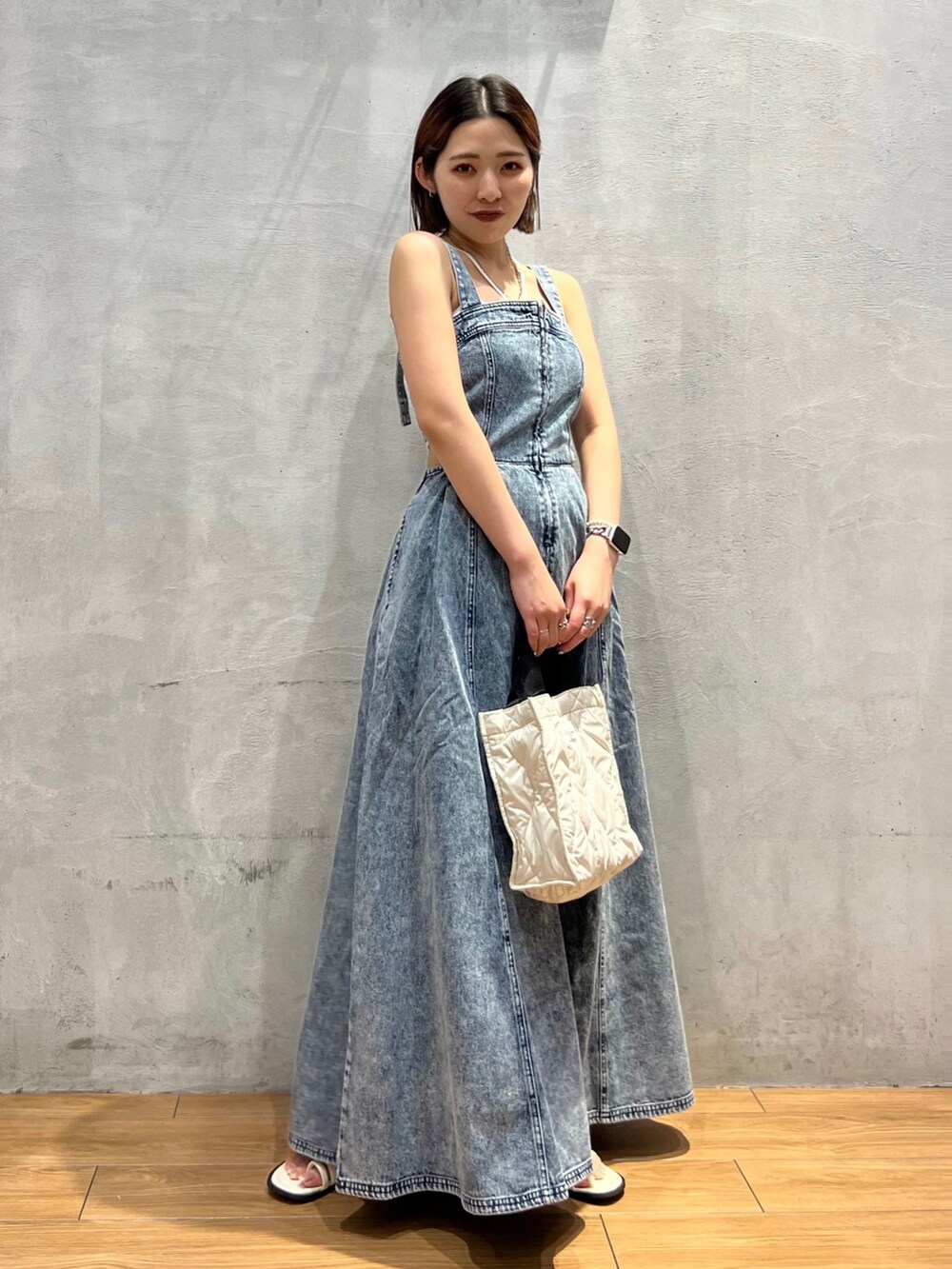 ホワイト系のショルダーバッグ、ブルー系のジャンパースカート、ホワイト系のサンダルを着用したレディースの夏コーディネートの2枚目の写真