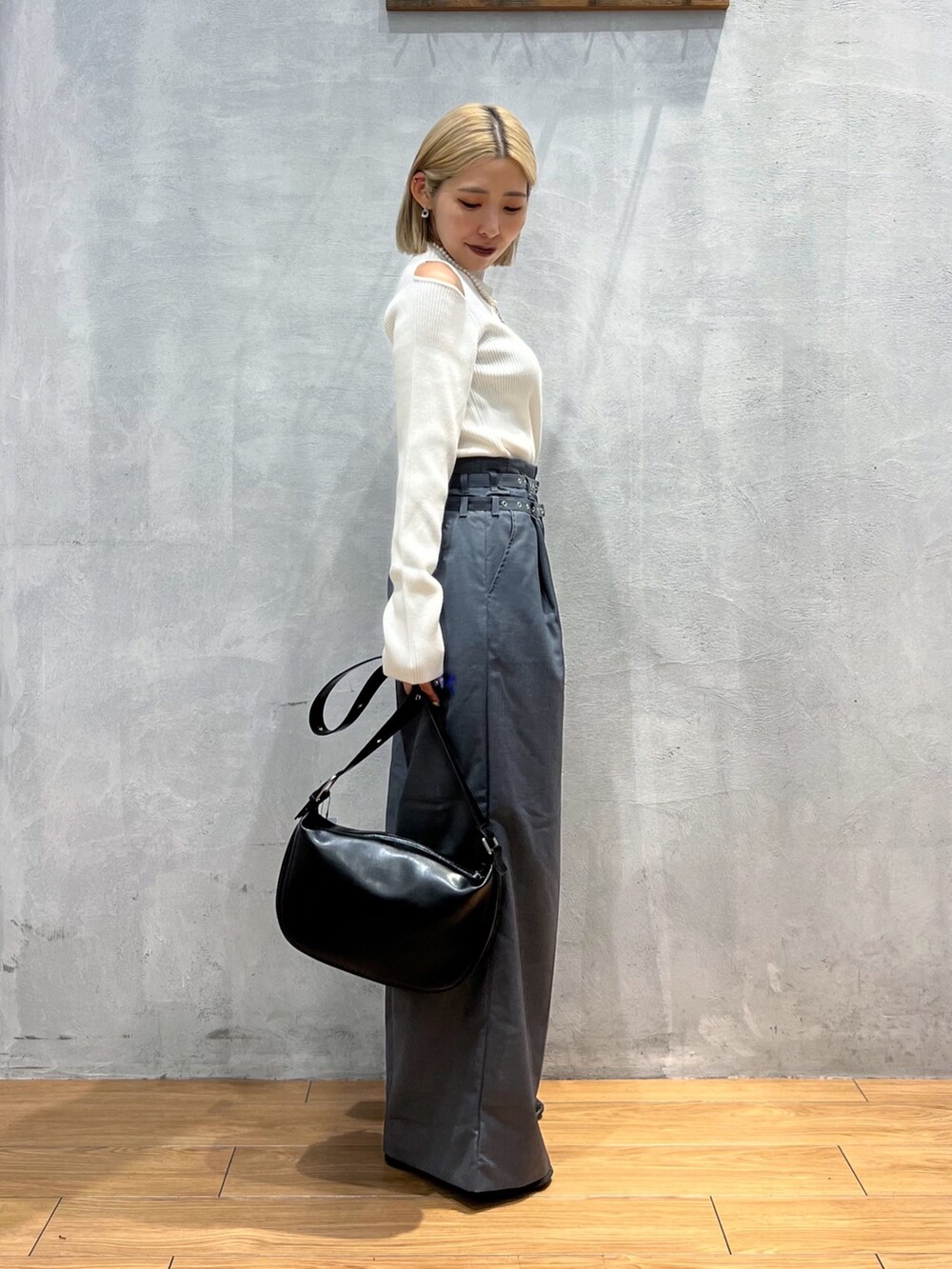 グレー系のスラックス、ホワイト系のトップス、ブラック系のショルダーバッグを着用したレディースの秋コーディネートの3枚目の写真