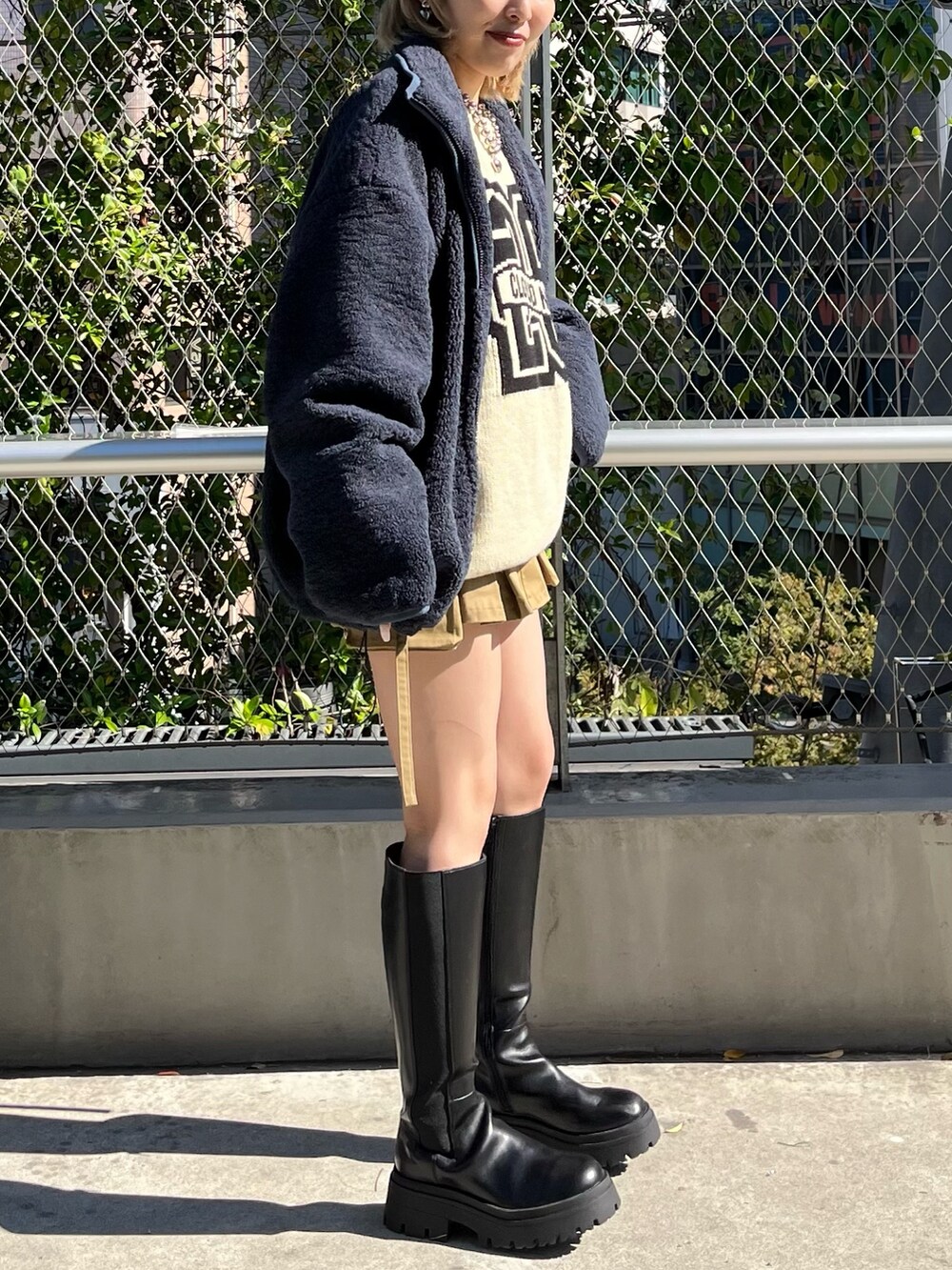 ブルー系のブルゾン、ホワイト系のニット/セーター、ベージュ系のスカートを着用したレディースの秋コーディネートの3枚目の写真