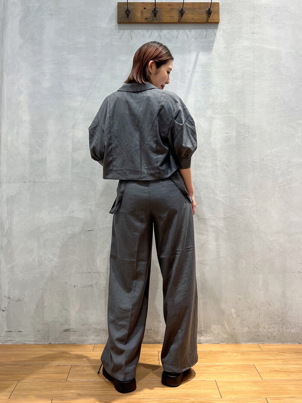 グレー系のスラックス、グレー系のテーラードジャケット、ホワイト系のキャミソールを着用したレディースの夏コーディネートの4枚目の写真