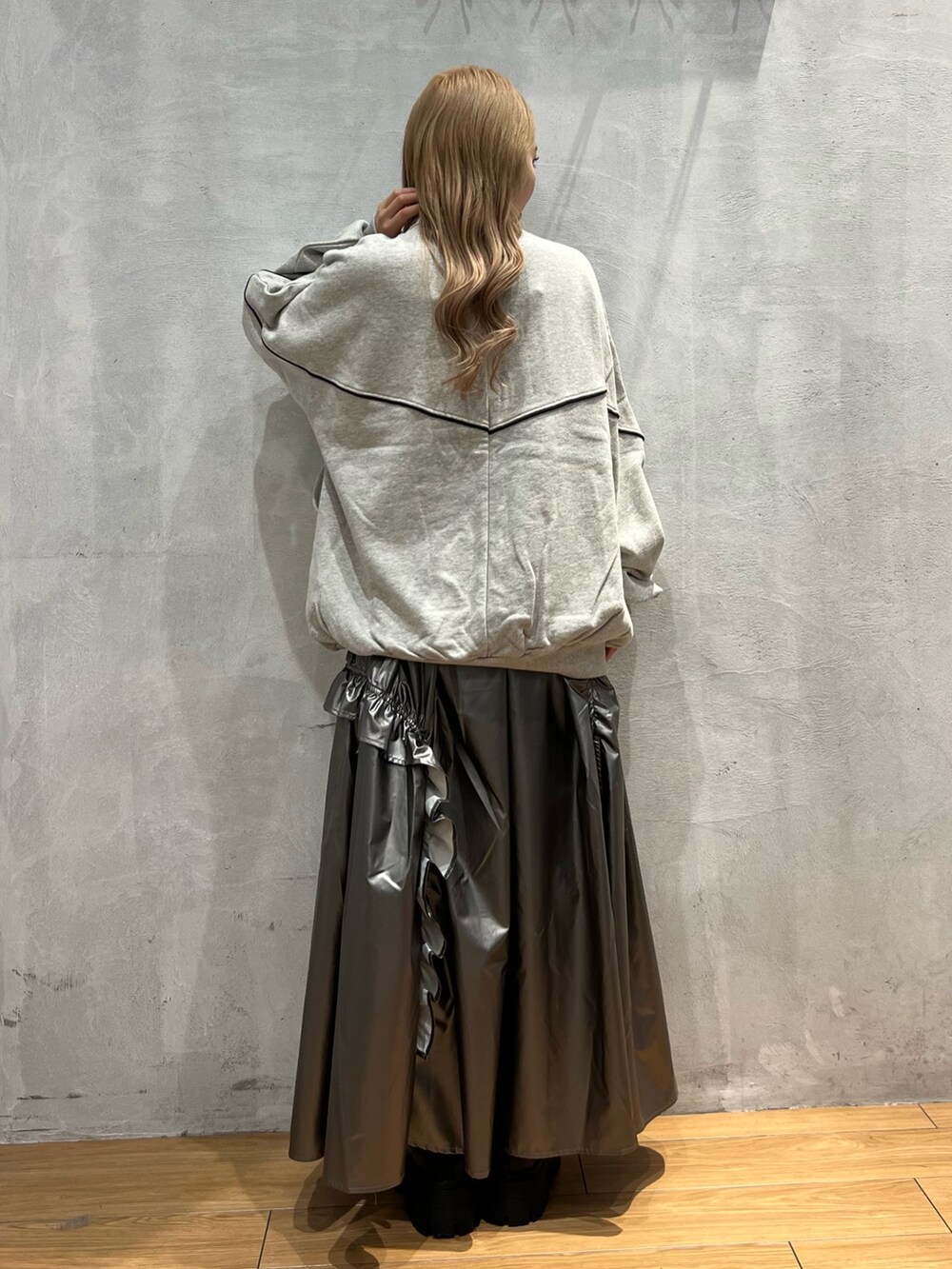 グレー系のスウェット、シルバー系のスカート、ブラック系のブーツを着用したレディースの秋コーディネートの3枚目の写真