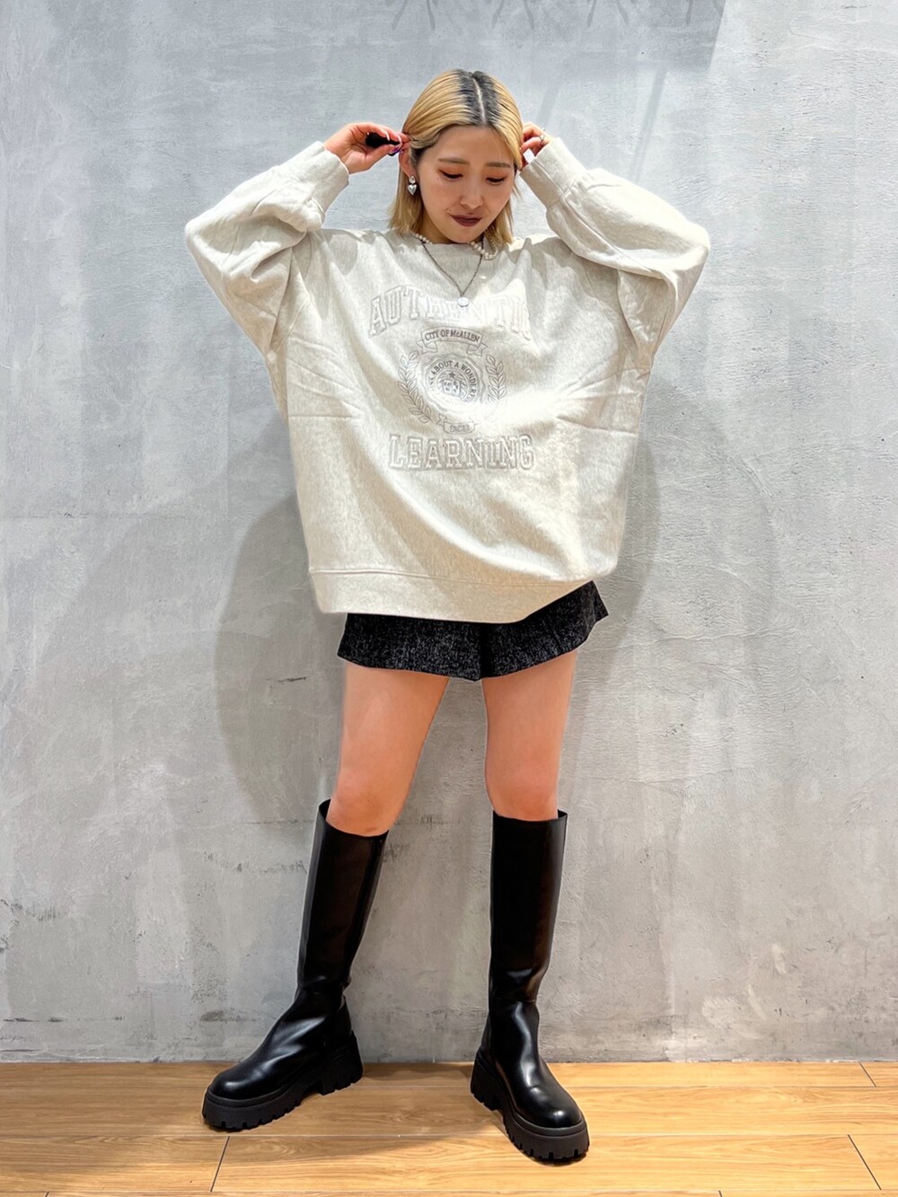 ベージュ系のスウェット、ブラック系のブーツ、ブラック系のパンツを着用したレディースの秋コーディネートの2枚目の写真