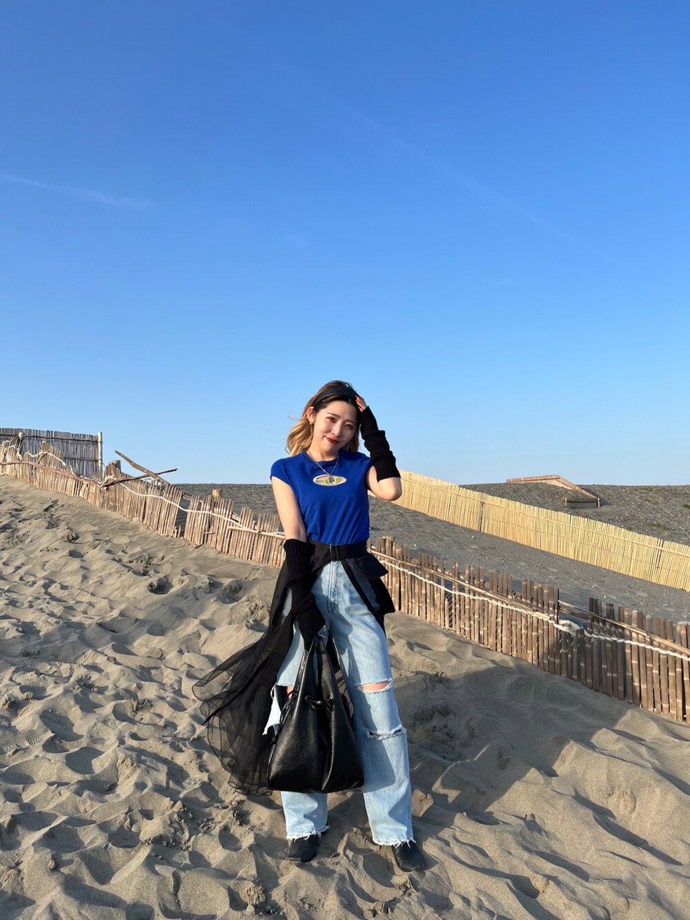 ブルー系のTシャツ/カットソー、ブラック系のスカート、ブルー系のデニムパンツを着用したレディースの春コーディネートの2枚目の写真