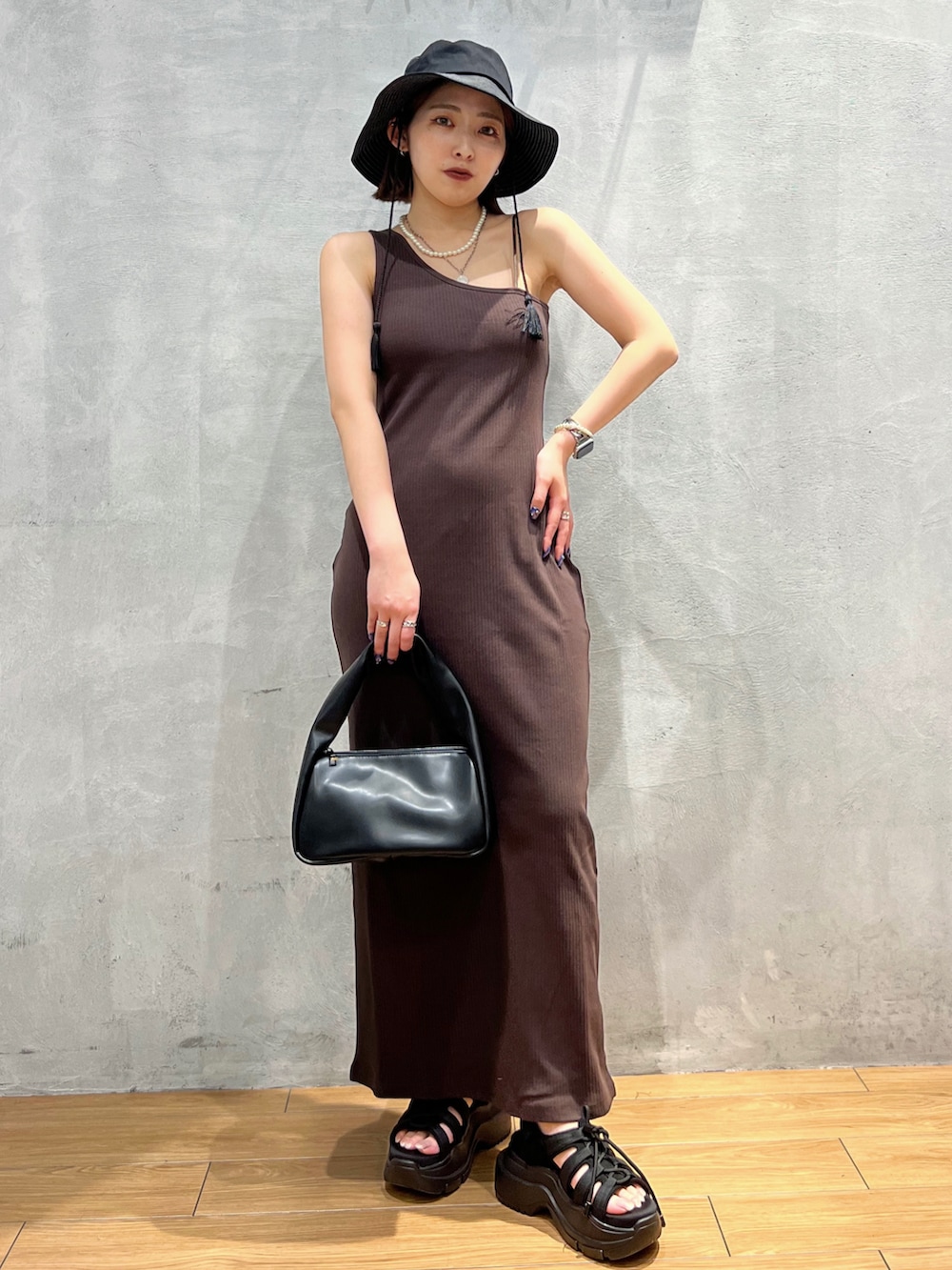 ブラウン系のワンピース、ブラック系のハンドバッグ、ブラック系のハットを着用したレディースの夏コーディネートの2枚目の写真