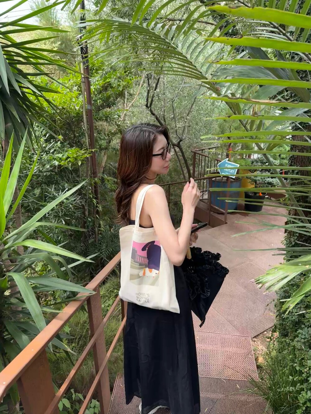 ホワイト系のスニーカー、ブラック系のワンピース、ホワイト系のトートバッグを着用したレディースの夏コーディネートの2枚目の写真