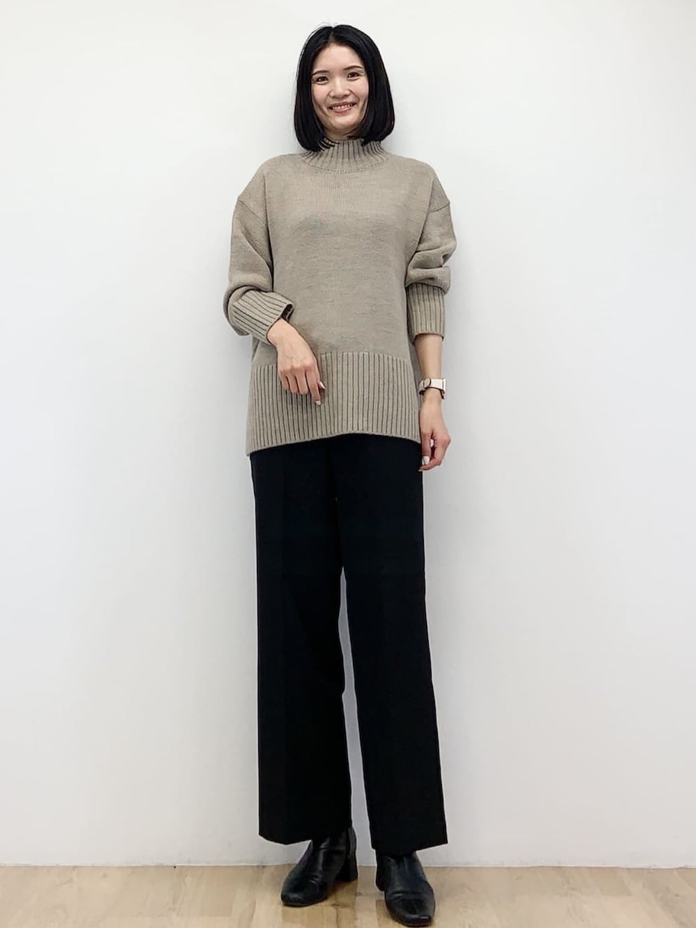 ブラック系のノーカラーコート、ベージュ系のニット/セーター、ブラック系のその他パンツを着用したレディースの秋コーディネートの5枚目の写真