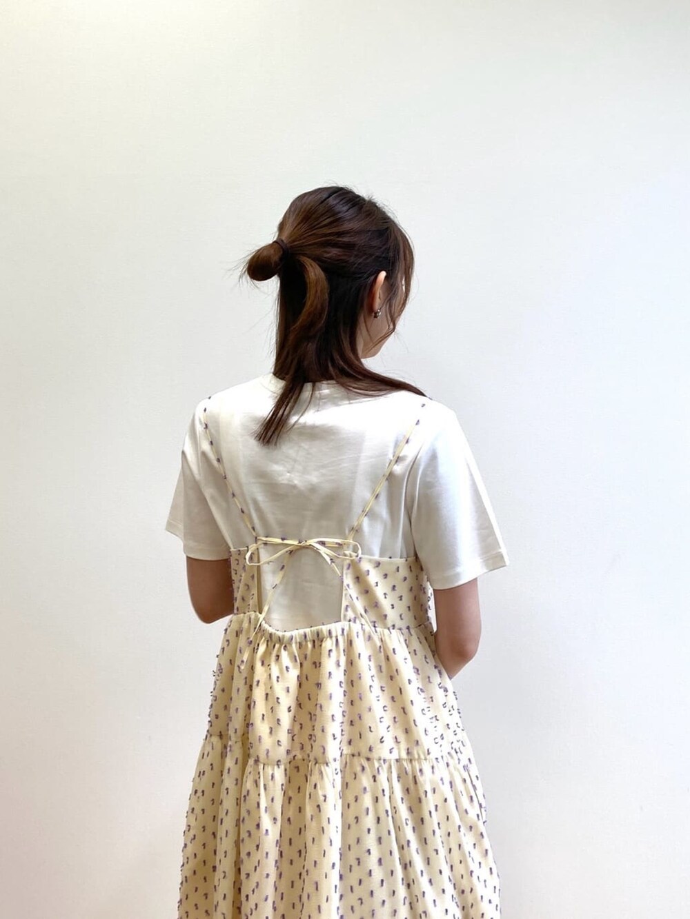 ホワイト系のワンピース、ホワイト系のTシャツ/カットソー、シルバー系のサンダルを着用したレディースの春コーディネートの6枚目の写真