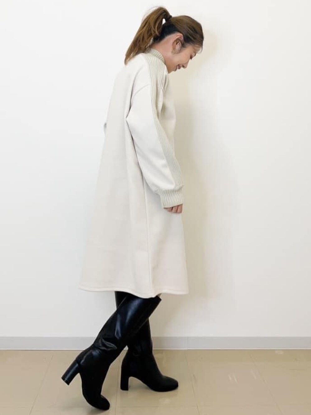 ホワイト系のワンピース、グレー系のショルダーバッグ、ブラック系のブーツを着用したレディースの冬コーディネートの2枚目の写真