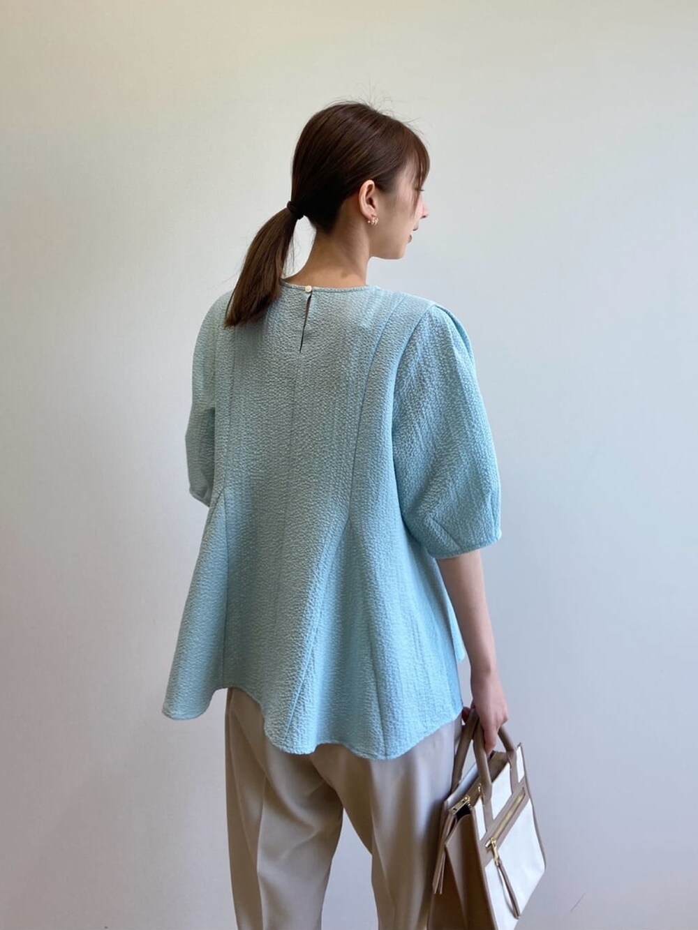 ブルー系のシャツ/ブラウス、ベージュ系のハンドバッグ、グレー系のその他パンツを着用したレディースの春コーディネートの8枚目の写真