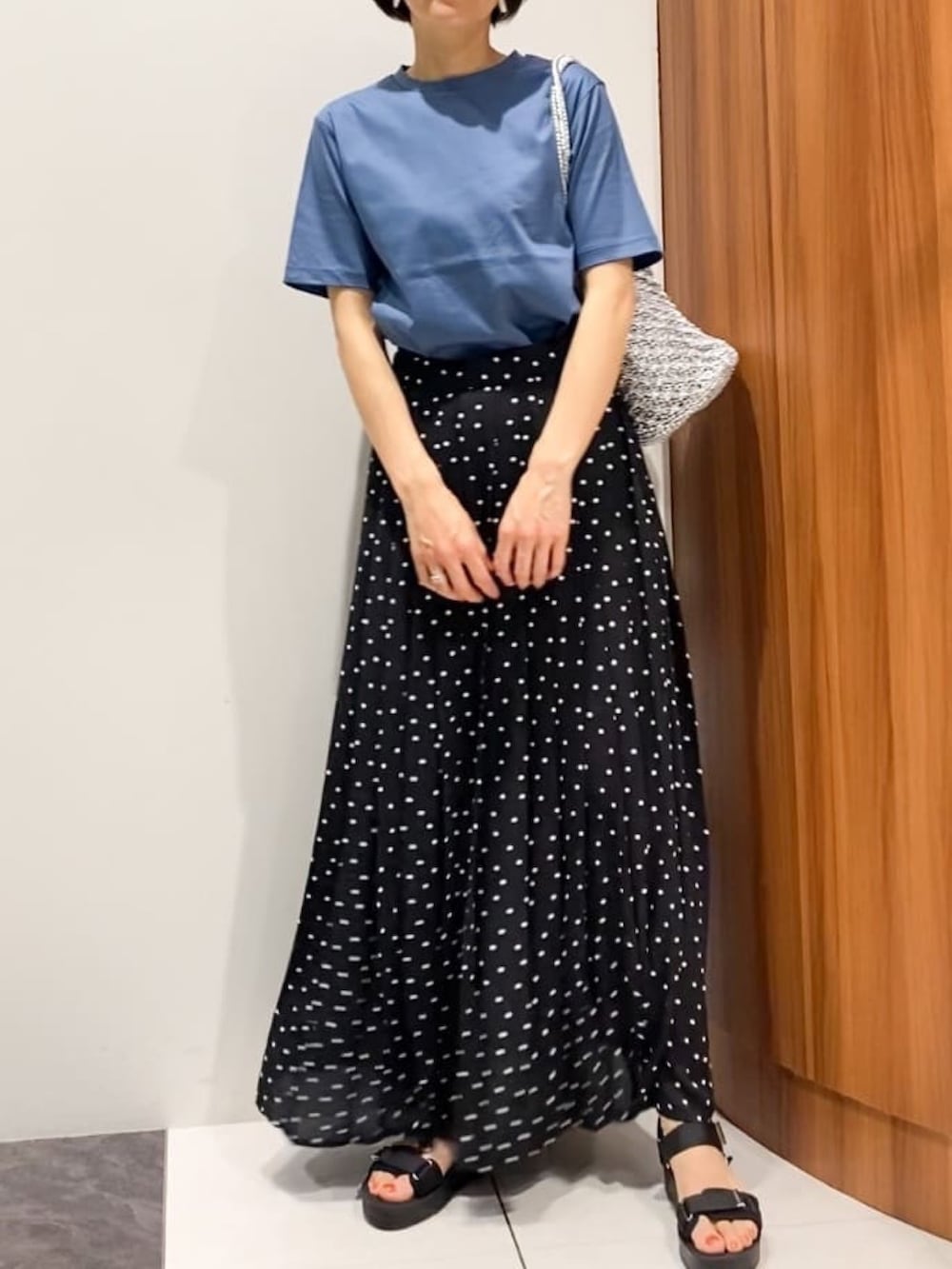 ブラック系のスカート、ブラック系のサンダル、シルバー系のトートバッグを着用したレディースの夏コーディネートの2枚目の写真