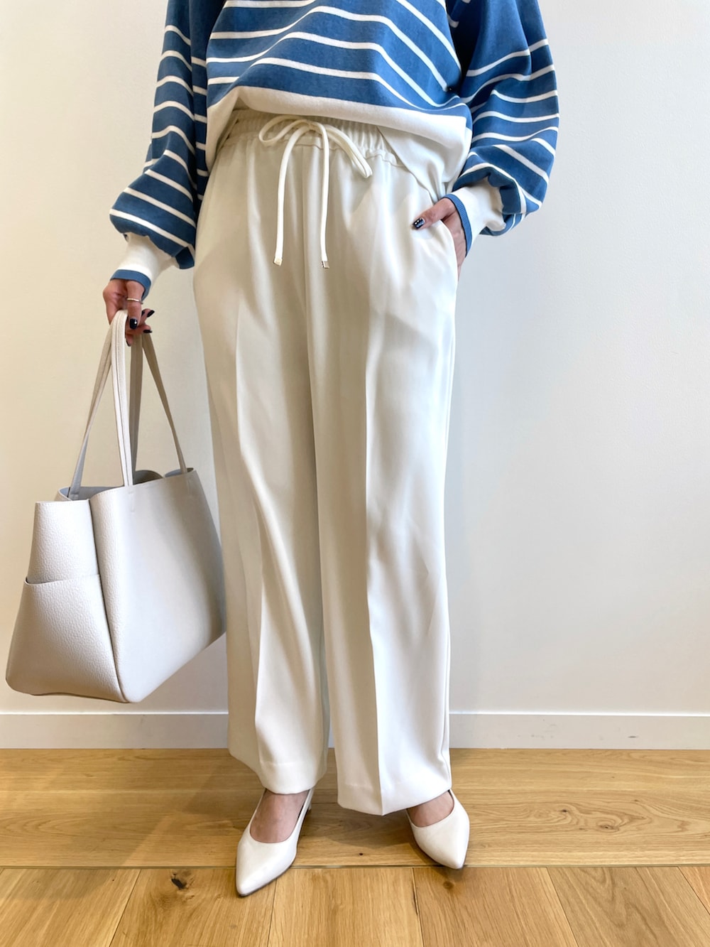 ホワイト系のノーカラーコート、ブルー系のニット/セーター、ホワイト系のその他パンツを着用したレディースの春コーディネートの5枚目の写真