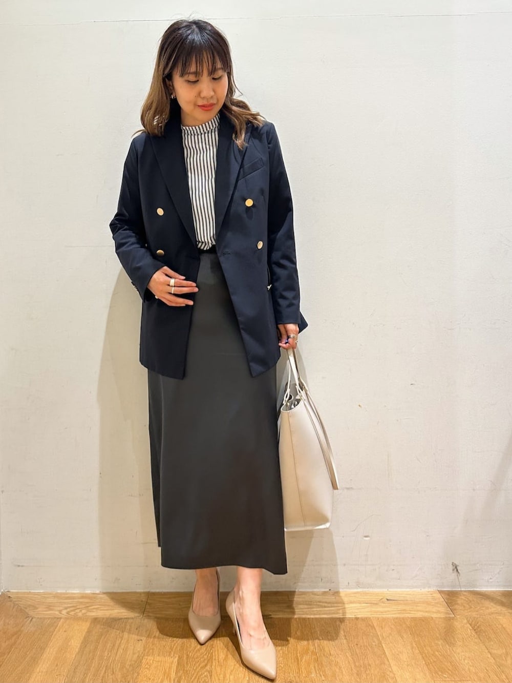 ブルー系のテーラードジャケット、ブラック系のシャツ/ブラウス、グレー系のスカートを着用したレディースの春コーディネートの2枚目の写真