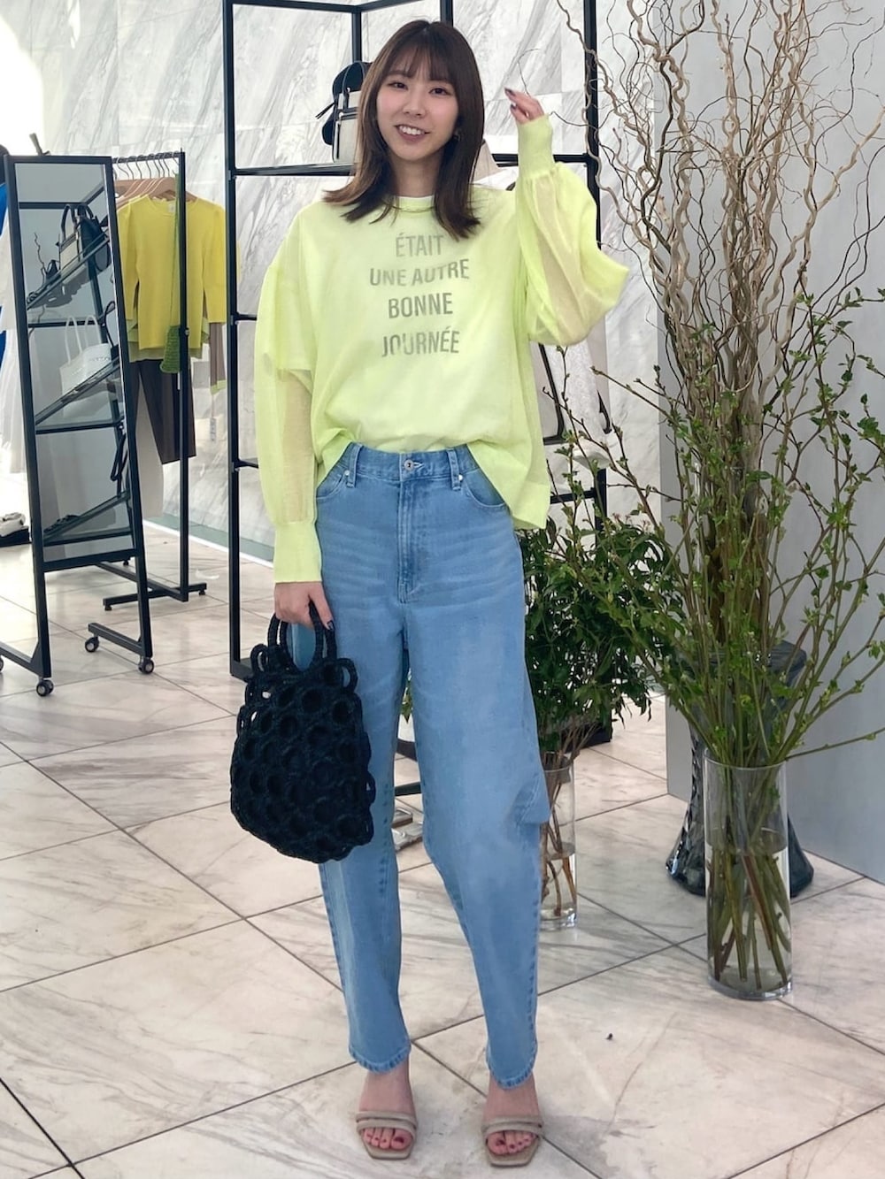 グリーン系のニット/セーター、ブルー系のデニムパンツ、ベージュ系のサンダルを着用したレディースの春コーディネートの2枚目の写真