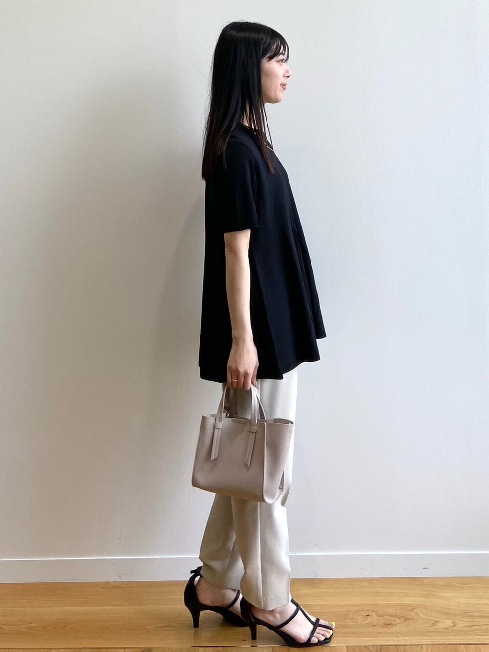 ブラック系のニット/セーター、ベージュ系のその他パンツ、ベージュ系のトートバッグを着用したレディースの春コーディネートの2枚目の写真