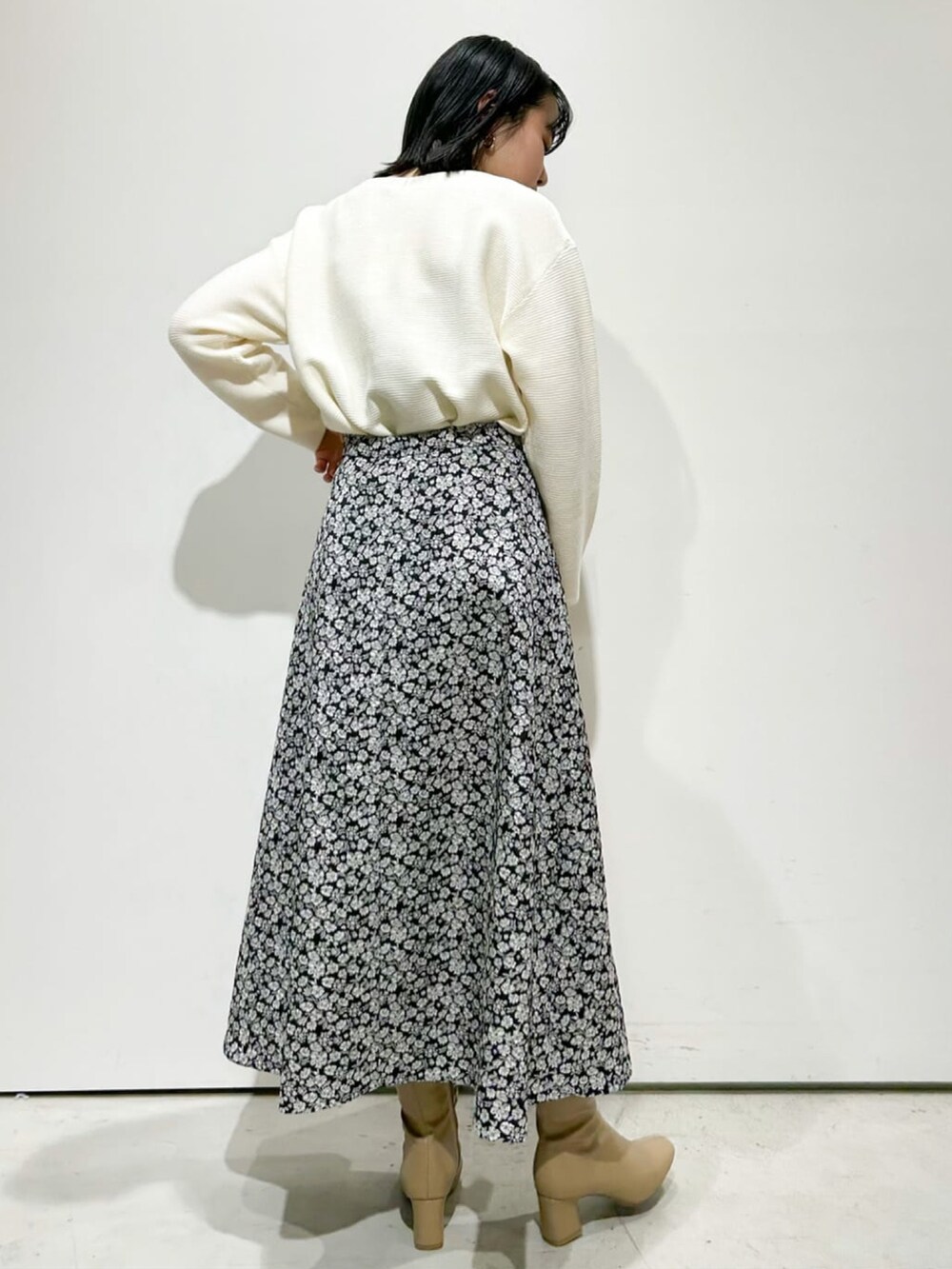 ホワイト系のニット/セーター、ブラック系のスカート、ベージュ系のブーツを着用したレディースの冬コーディネートの2枚目の写真