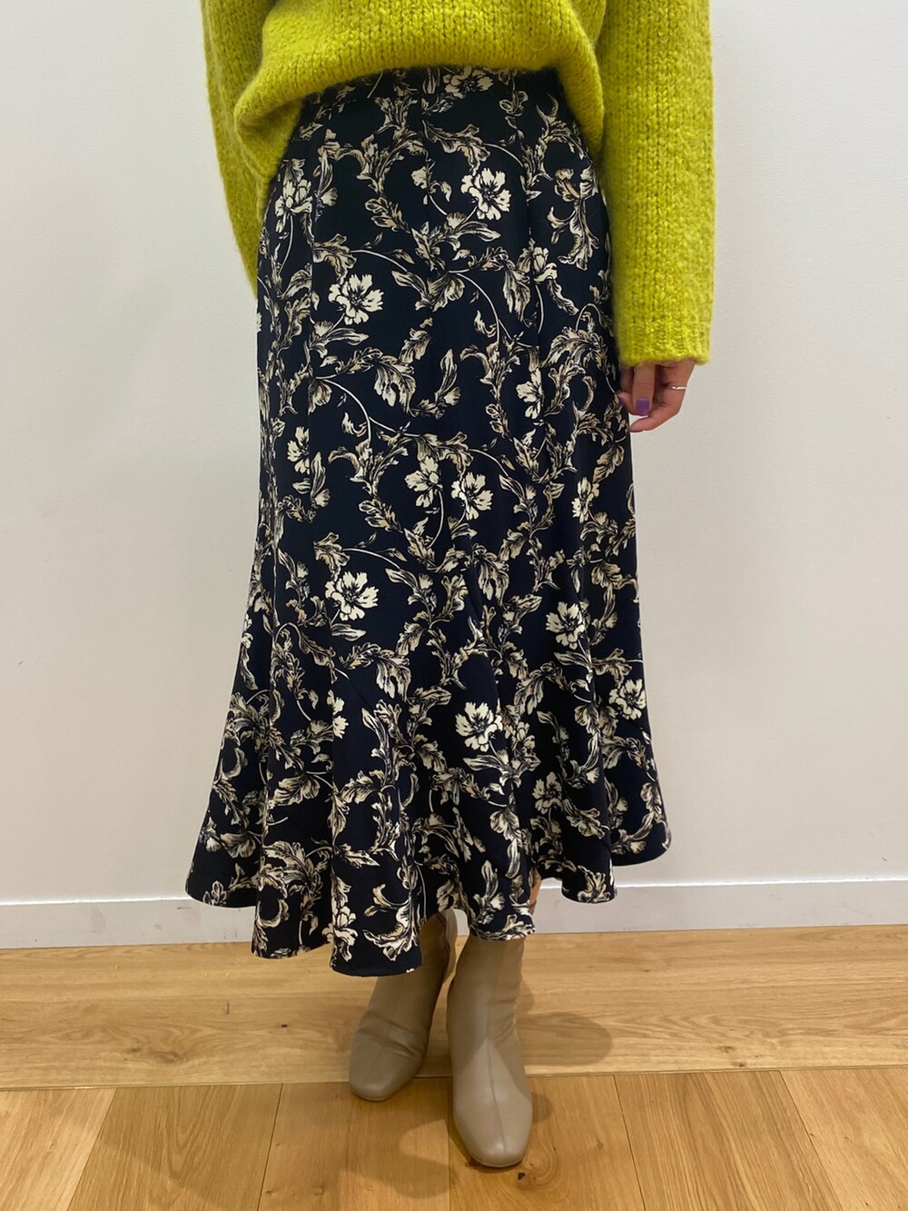 ホワイト系のノーカラーコート、イエロー系のニット/セーター、ベージュ系のブーツを着用したレディースの秋コーディネートの4枚目の写真