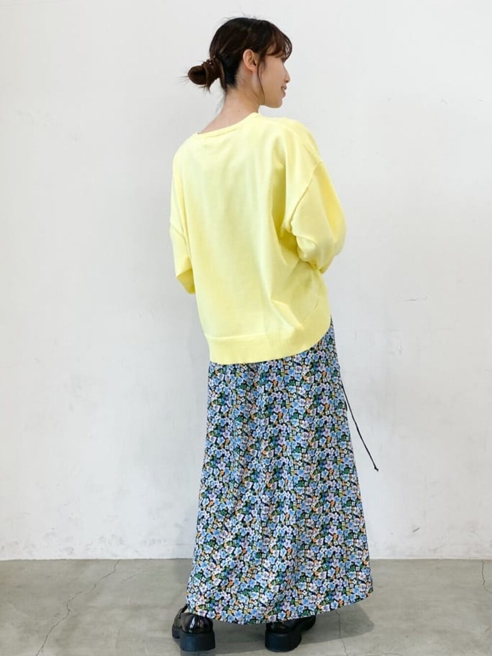 イエロー系のニット/セーター、ブラック系のスカート、ブラック系のショルダーバッグを着用したレディースの冬コーディネートの2枚目の写真