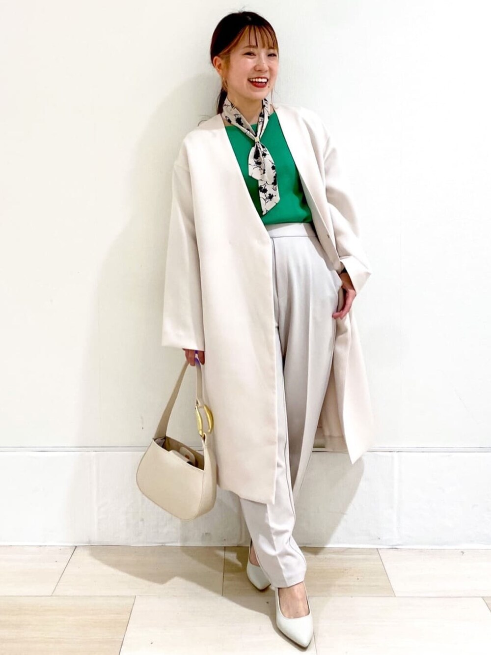 ホワイト系のノーカラーコート、グリーン系のニット/セーター、ホワイト系のパンプスを着用したレディースの冬コーディネートの3枚目の写真