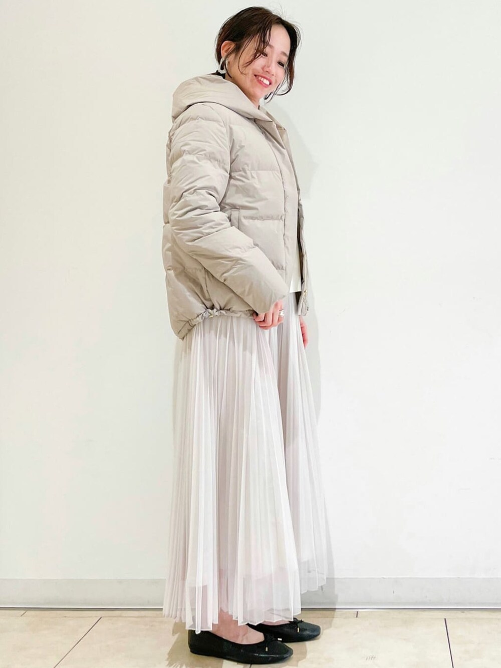 ベージュ系のダウンジャケット/コート、ベージュ系のスカート、ホワイト系のニット/セーターを着用したレディースの冬コーディネートの2枚目の写真