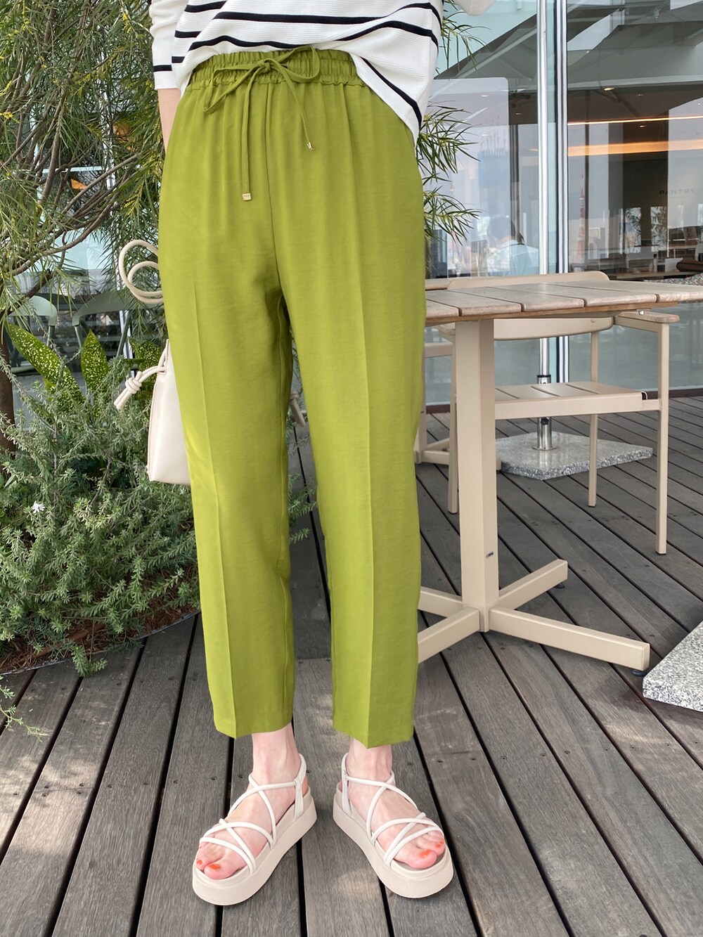 ホワイト系のニット/セーター、グリーン系のその他パンツ、ベージュ系のショルダーバッグを着用したレディースの春コーディネートの3枚目の写真