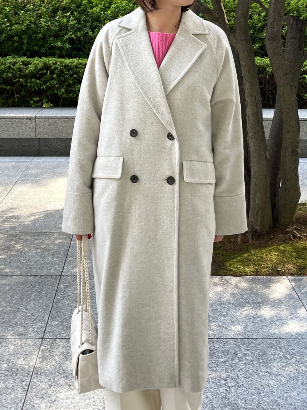 ピンク系のニット/セーター、ベージュ系のチェスターコート、ホワイト系のブーツを着用したレディースの秋コーディネートの3枚目の写真