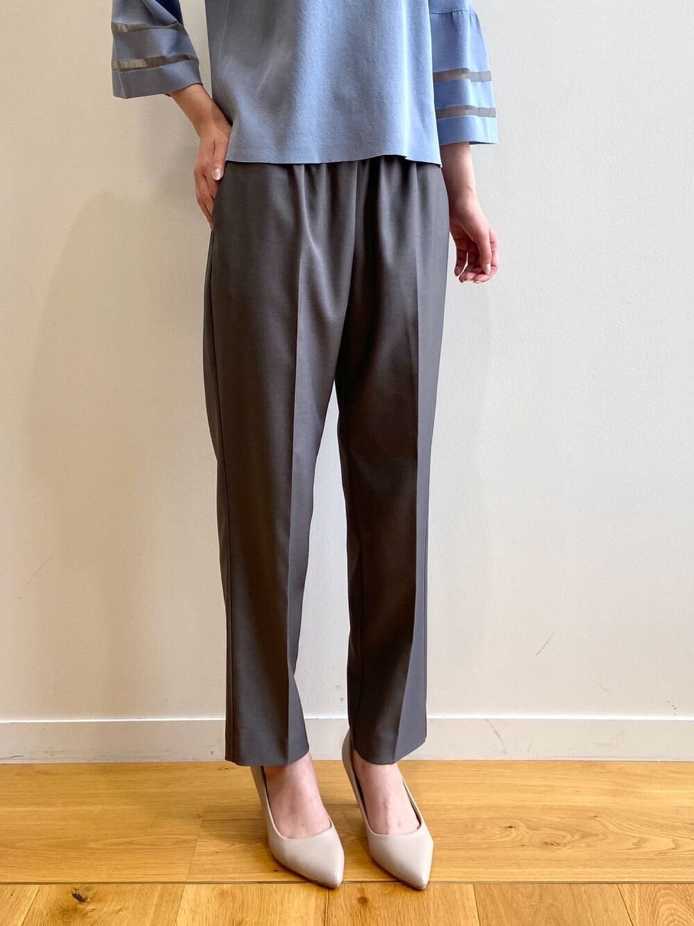 グレー系のその他パンツ、ベージュ系のパンプス、ブルー系のニット/セーターを着用したレディースの秋コーディネートの7枚目の写真