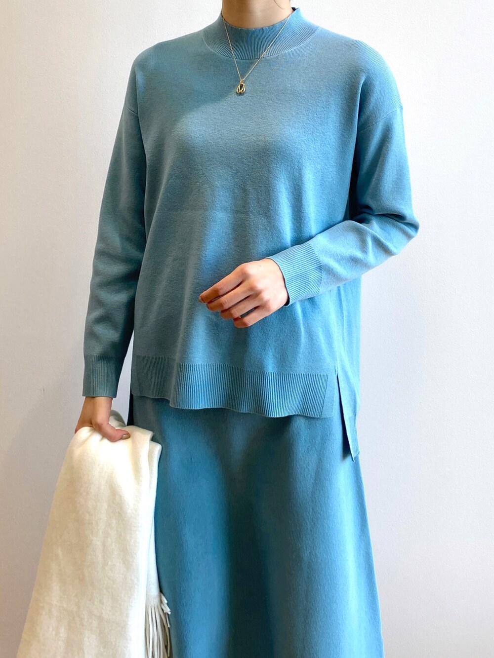 ブルー系のニット/セーター、ブルー系のスカート、ホワイト系のブーツを着用したレディースの冬コーディネートの4枚目の写真