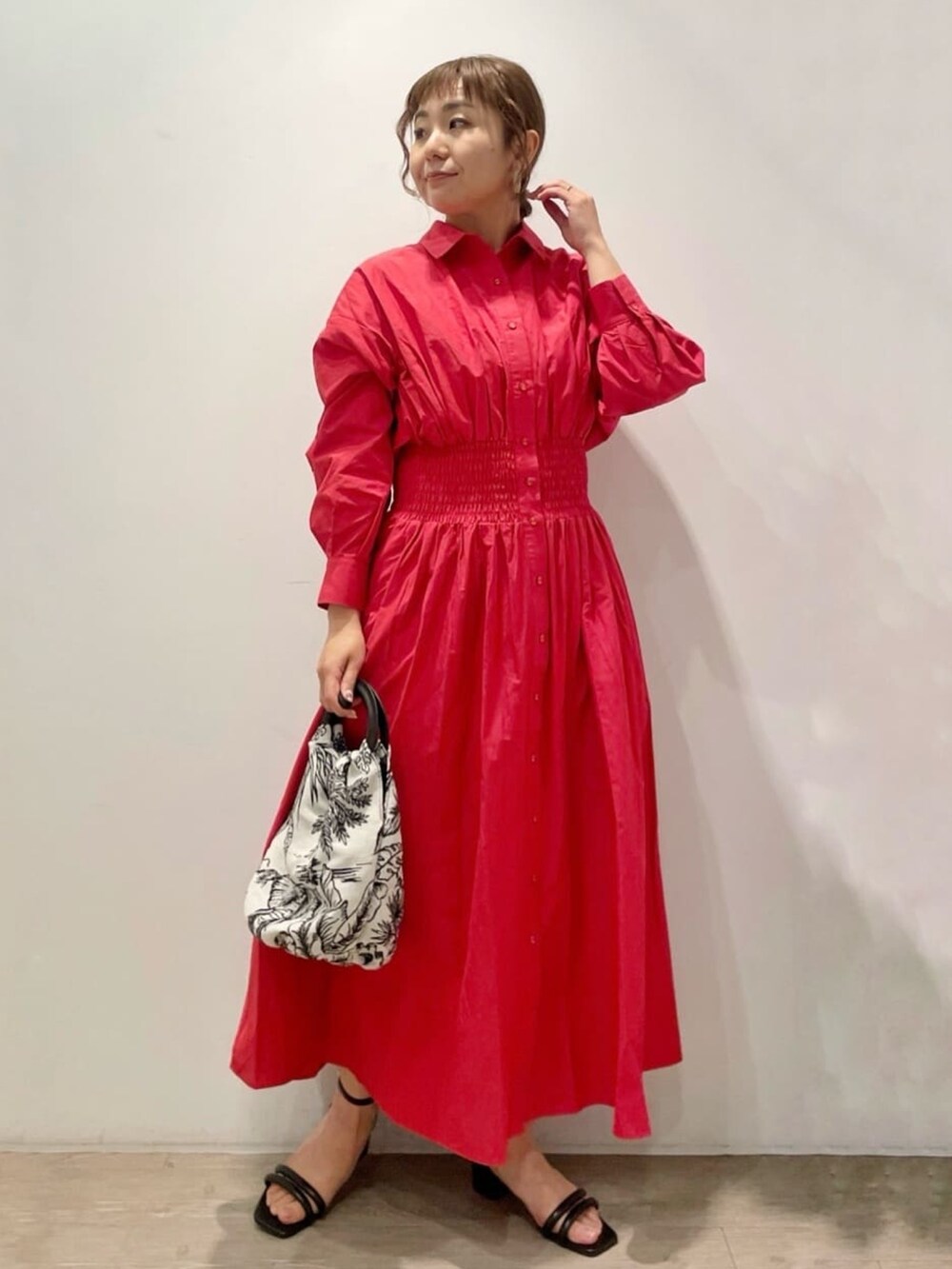 レッド系のワンピース、ホワイト系のハンドバッグ、ブラック系のサンダルを着用したレディースの春コーディネートの3枚目の写真