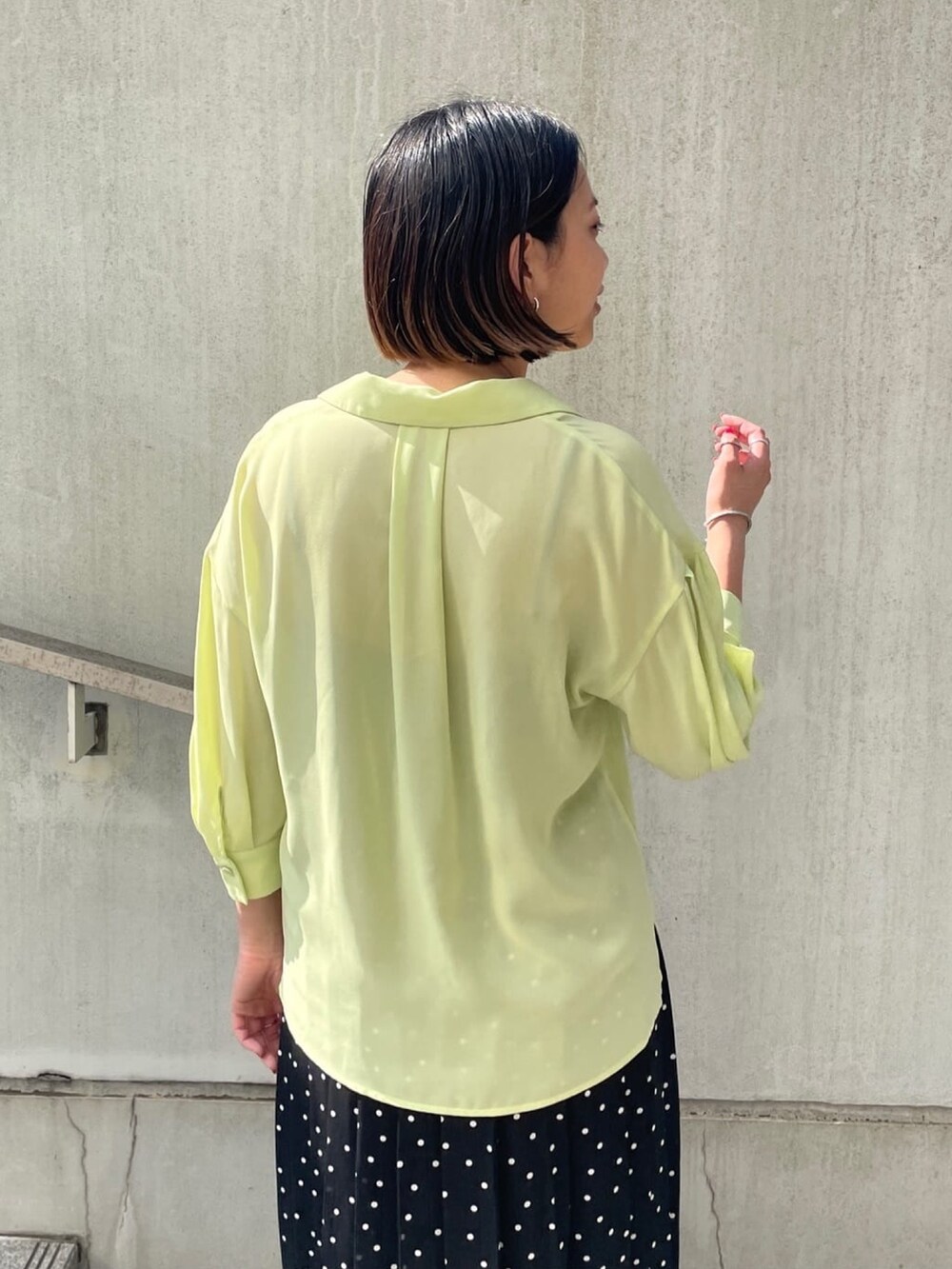 グリーン系のシャツ/ブラウス、ブラック系のスカート、ブラック系のサンダルを着用したレディースの春コーディネートの5枚目の写真