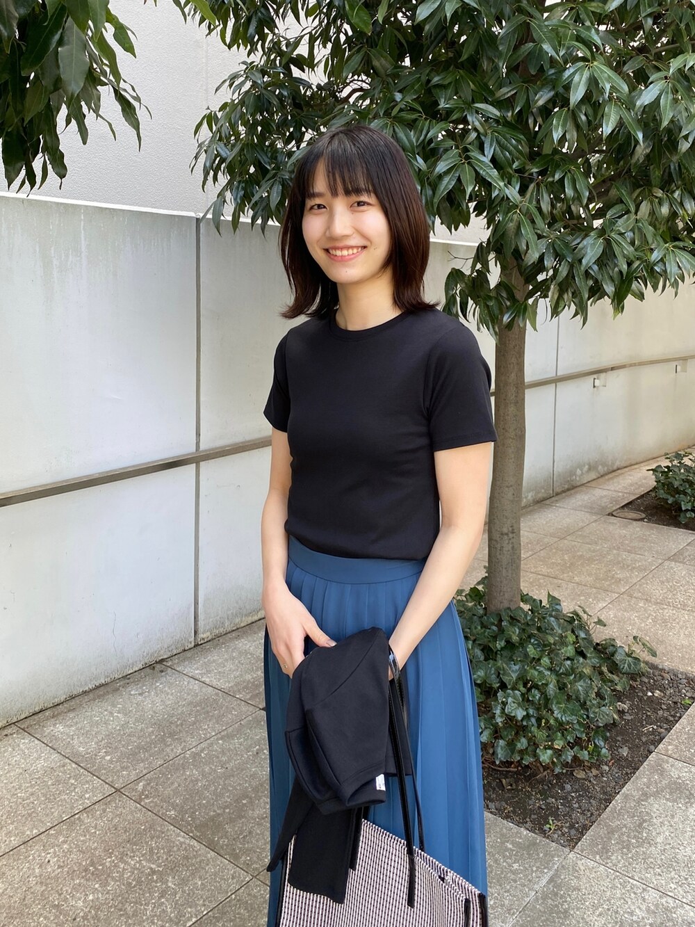 ブルー系のスカート、ブラウン系のサンダル、ブラック系のトートバッグを着用したレディースの春コーディネートの4枚目の写真